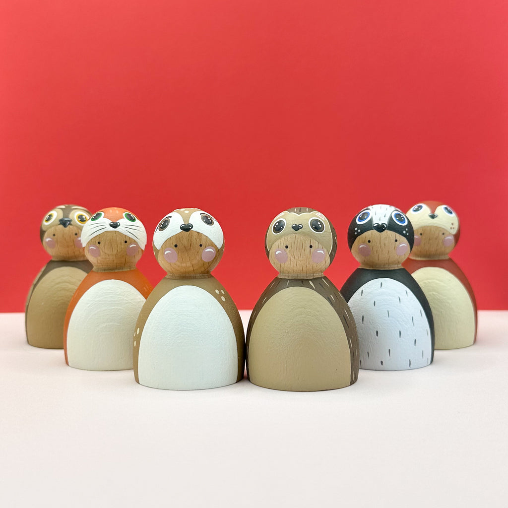 Wooden dolls resembling woodland animals on a red background