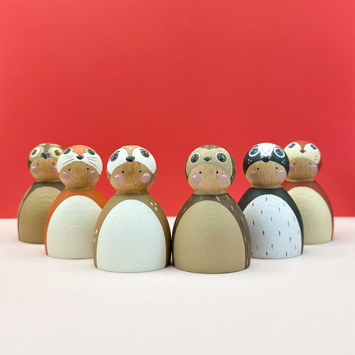 Wooden dolls resembling woodland animals on a red background