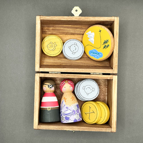 Wooden toy treasure chest with wooden peg dolls, wooden coins and a round disc shaped treasure map