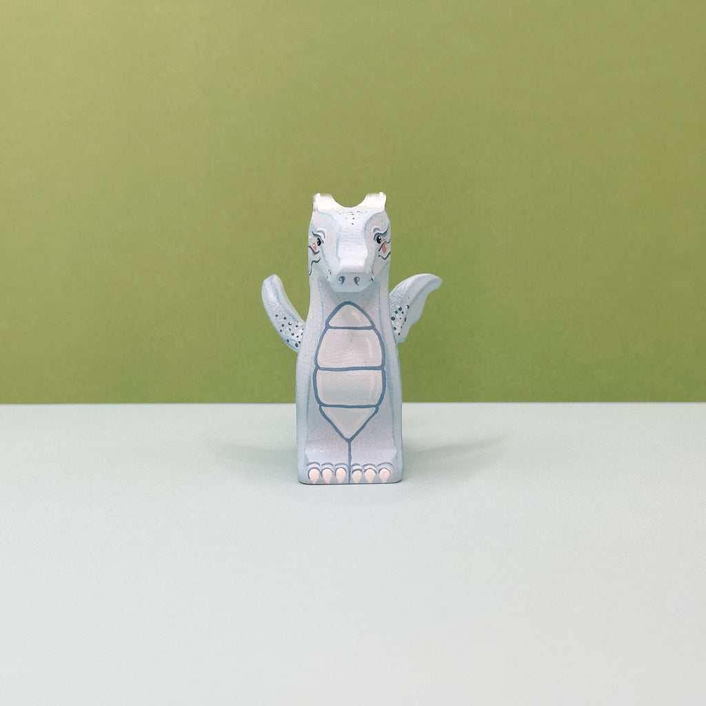 A small wooden light blue dragon on a green background