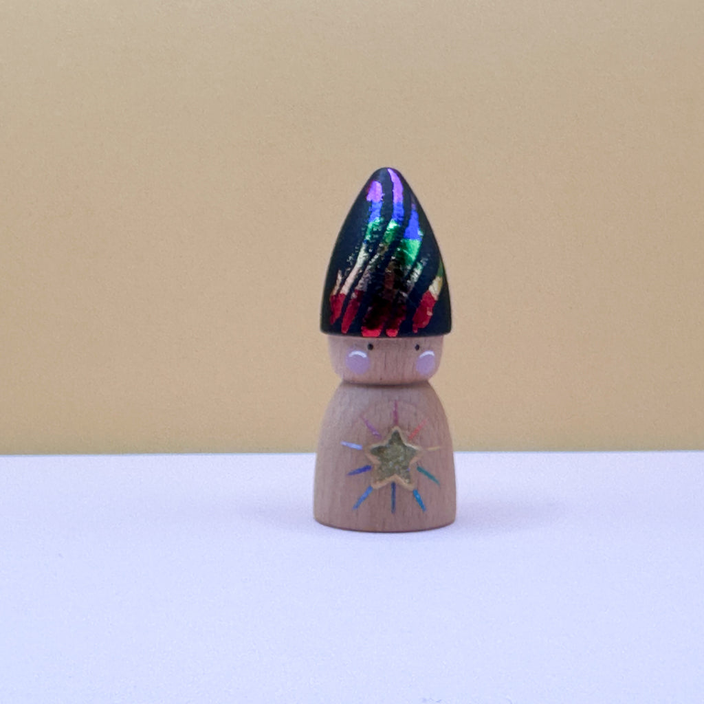 Wooden peg doll with colorful hat on a white surface and beige background