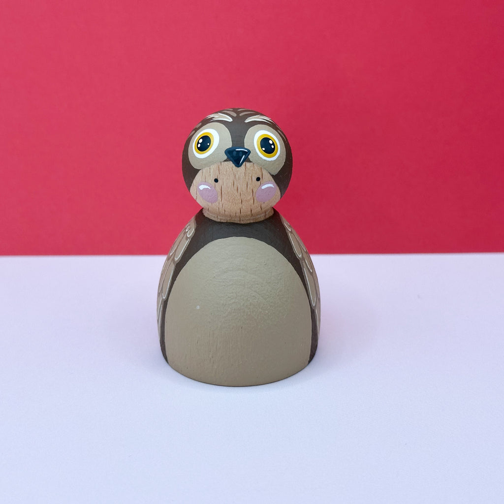 Wooden doll dressed as an owl with a red background