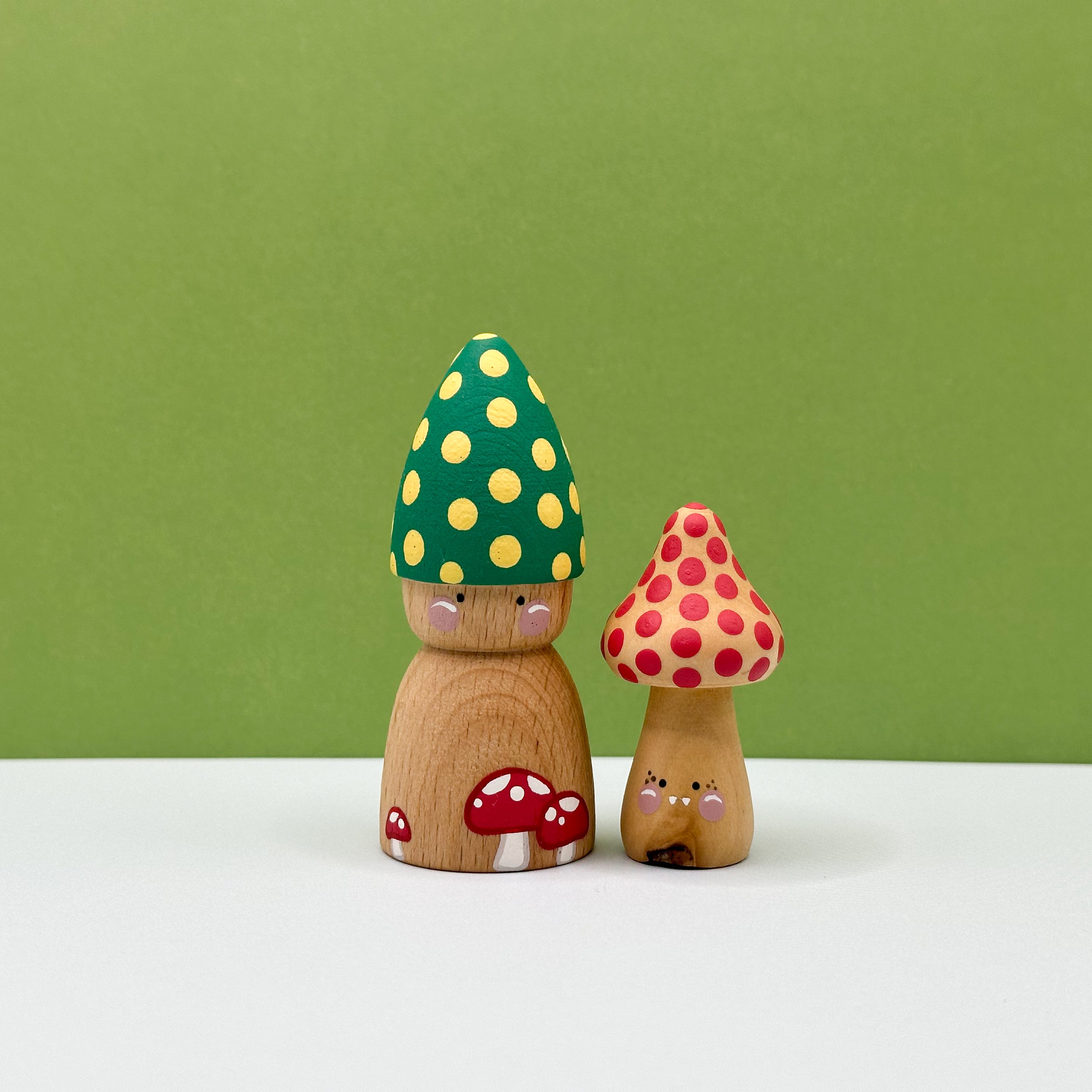 Wooden mushroom figurines with colorful caps on a white surface and green background