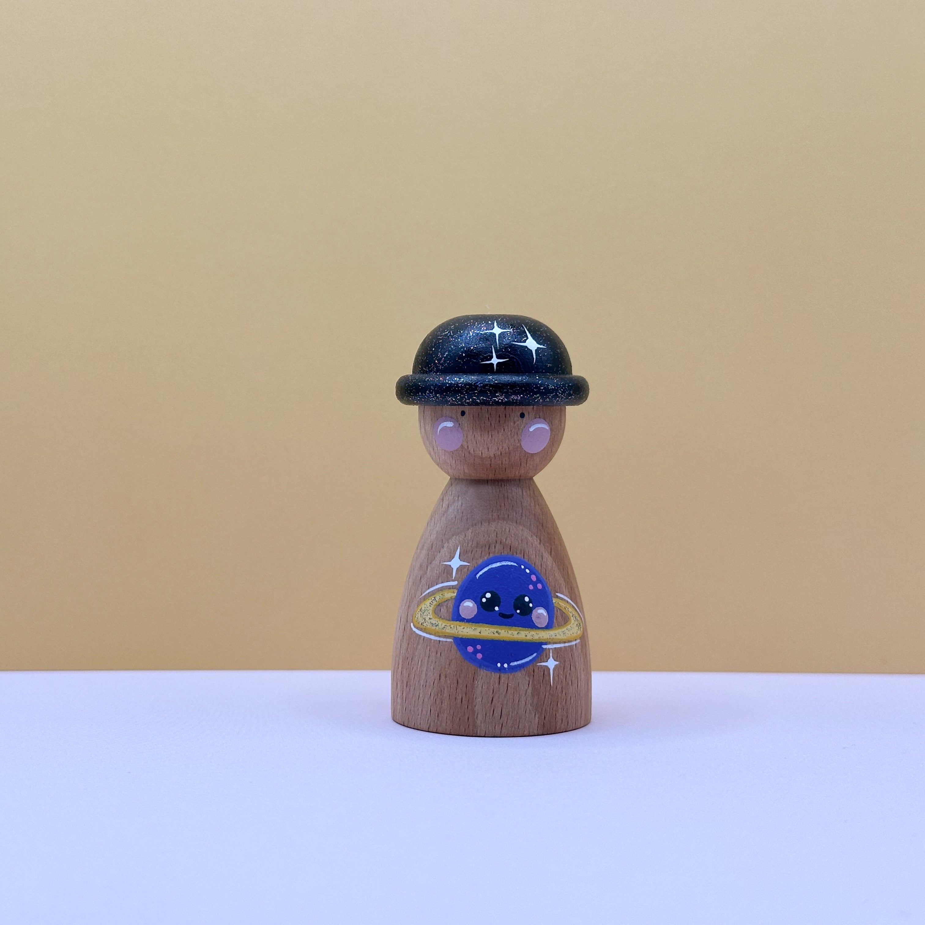 Wooden peg doll with a space-themed design on a beige background