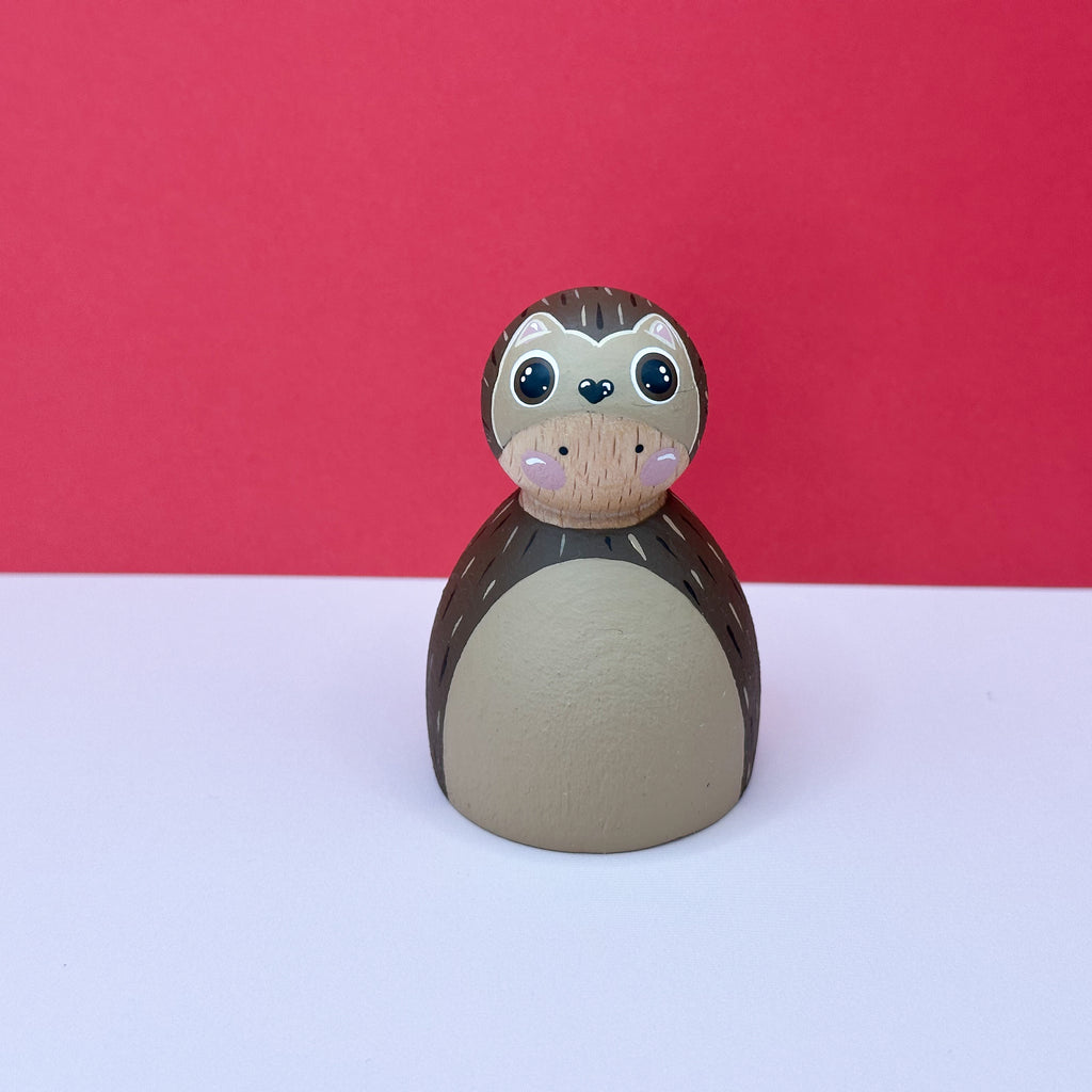 Wooden doll dressed as a hedgehog on a white surface with a red background