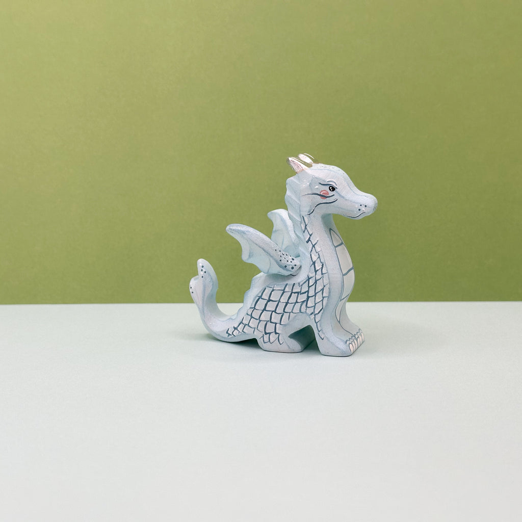 A small wooden light blue dragon on a green background