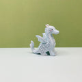 A small wooden light blue dragon on a green background