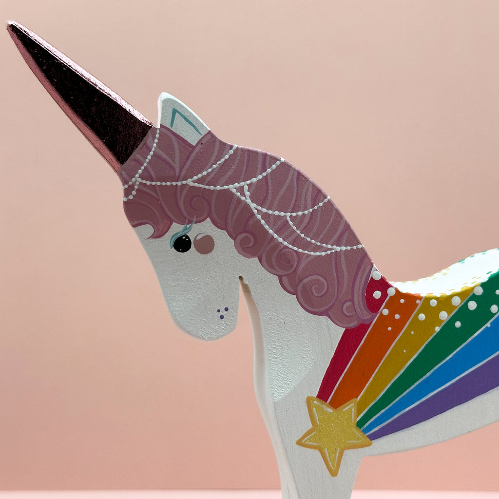 Unicorn figurine with rainbow and star design on a beige background