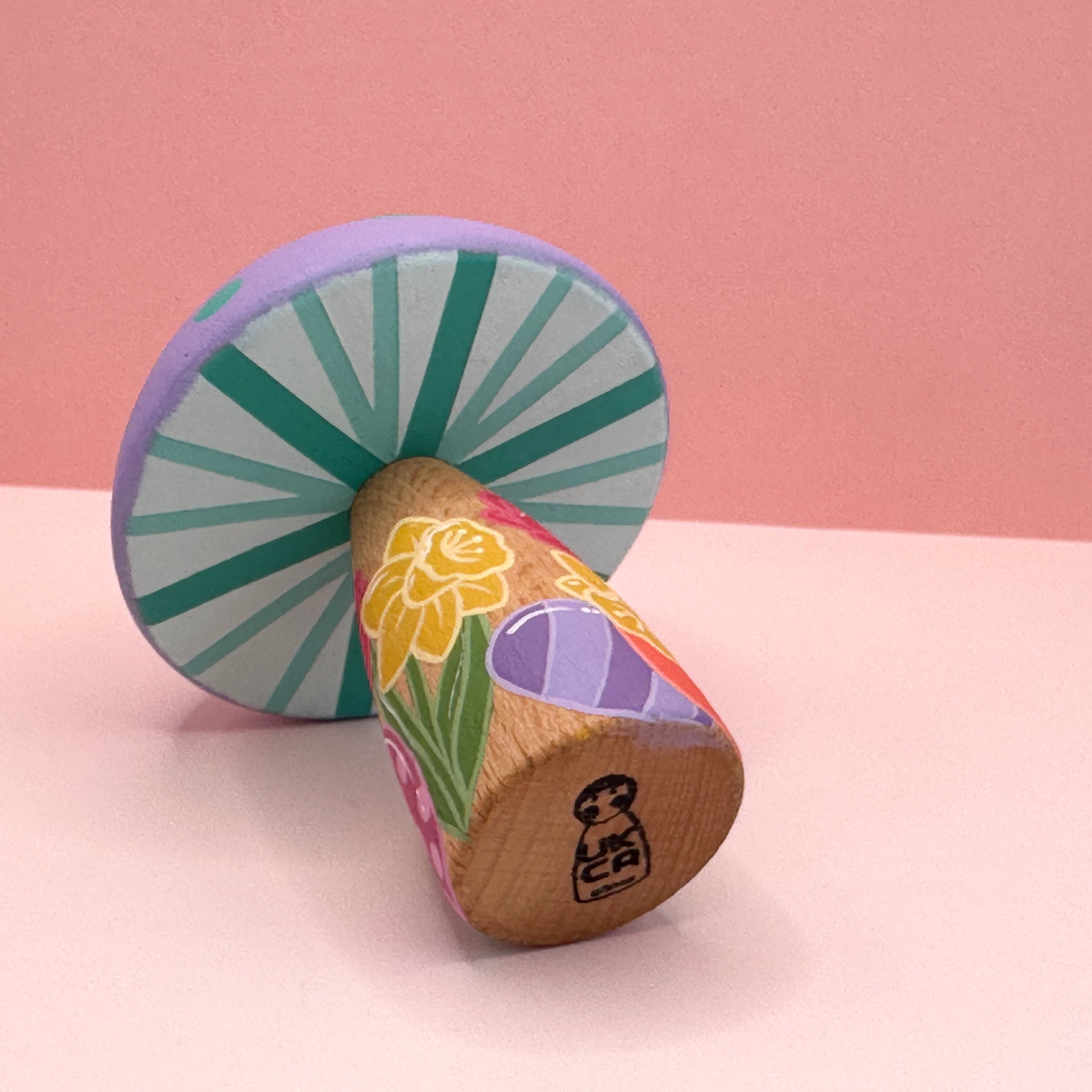 Colorful wooden toy with a starburst design on a pink background