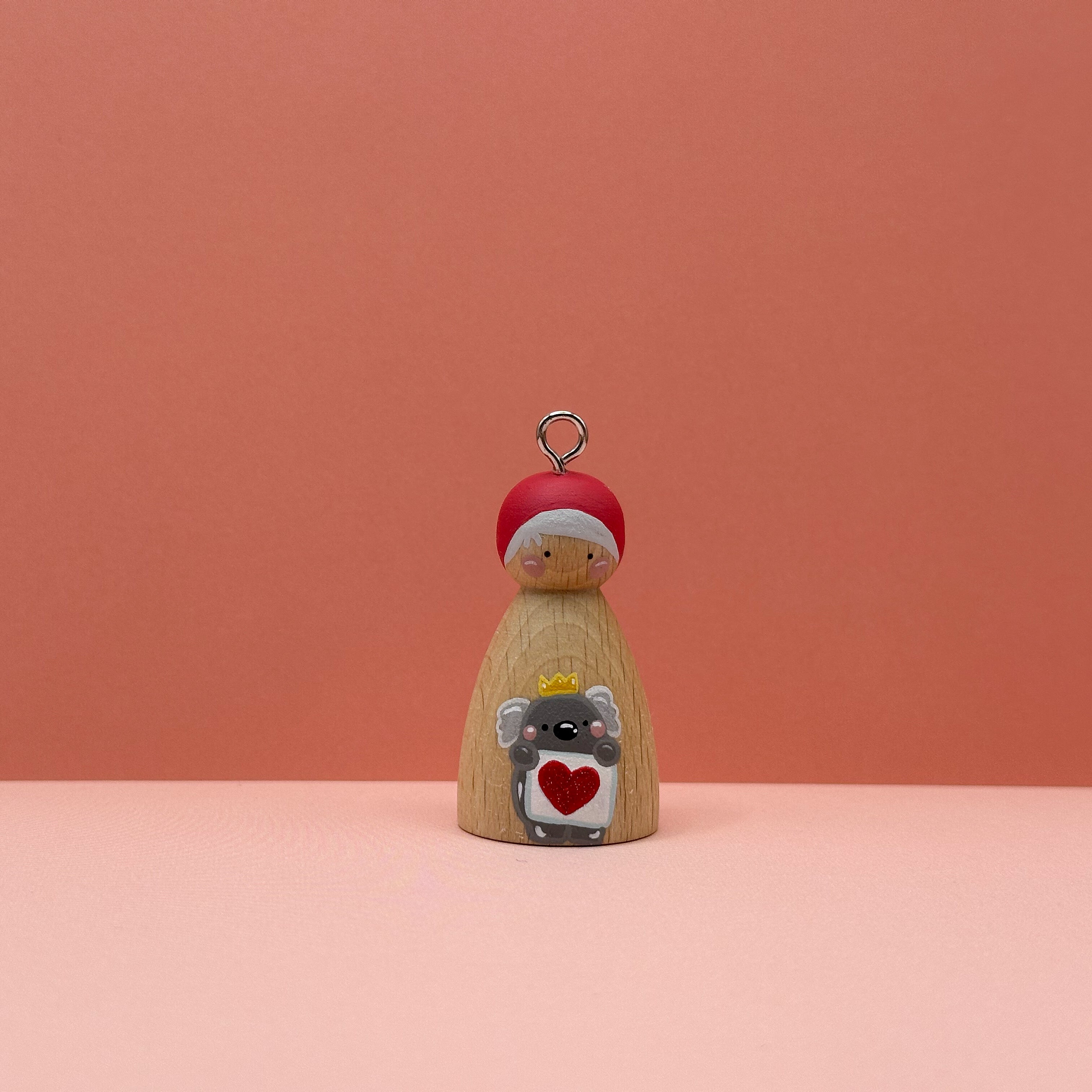 Small peg doll keyring with a koala holding a heart sign painted on its body with a peach background