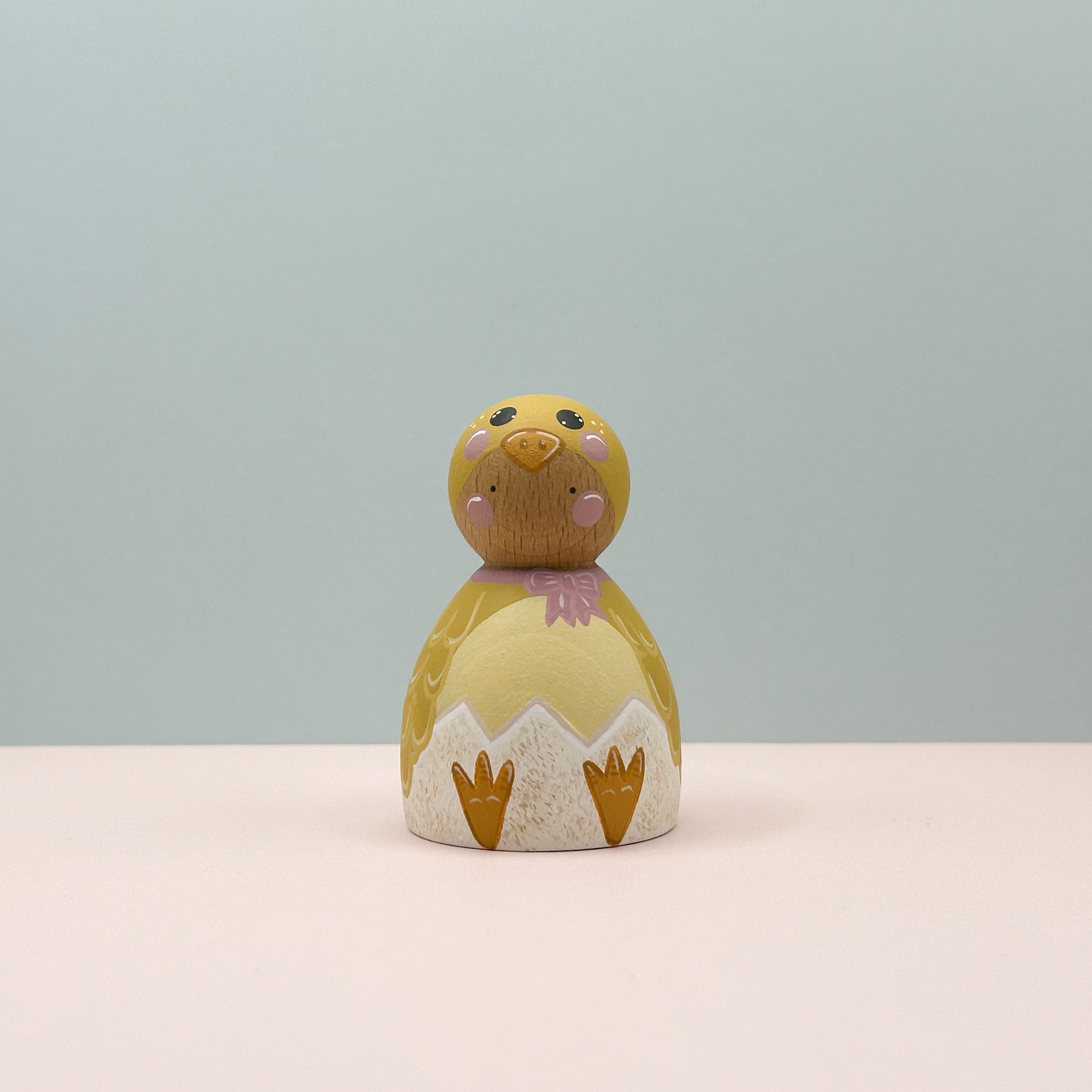 Small wooden chick figurine with a light blue background