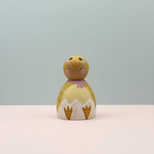 Small wooden chick figurine with a light blue background