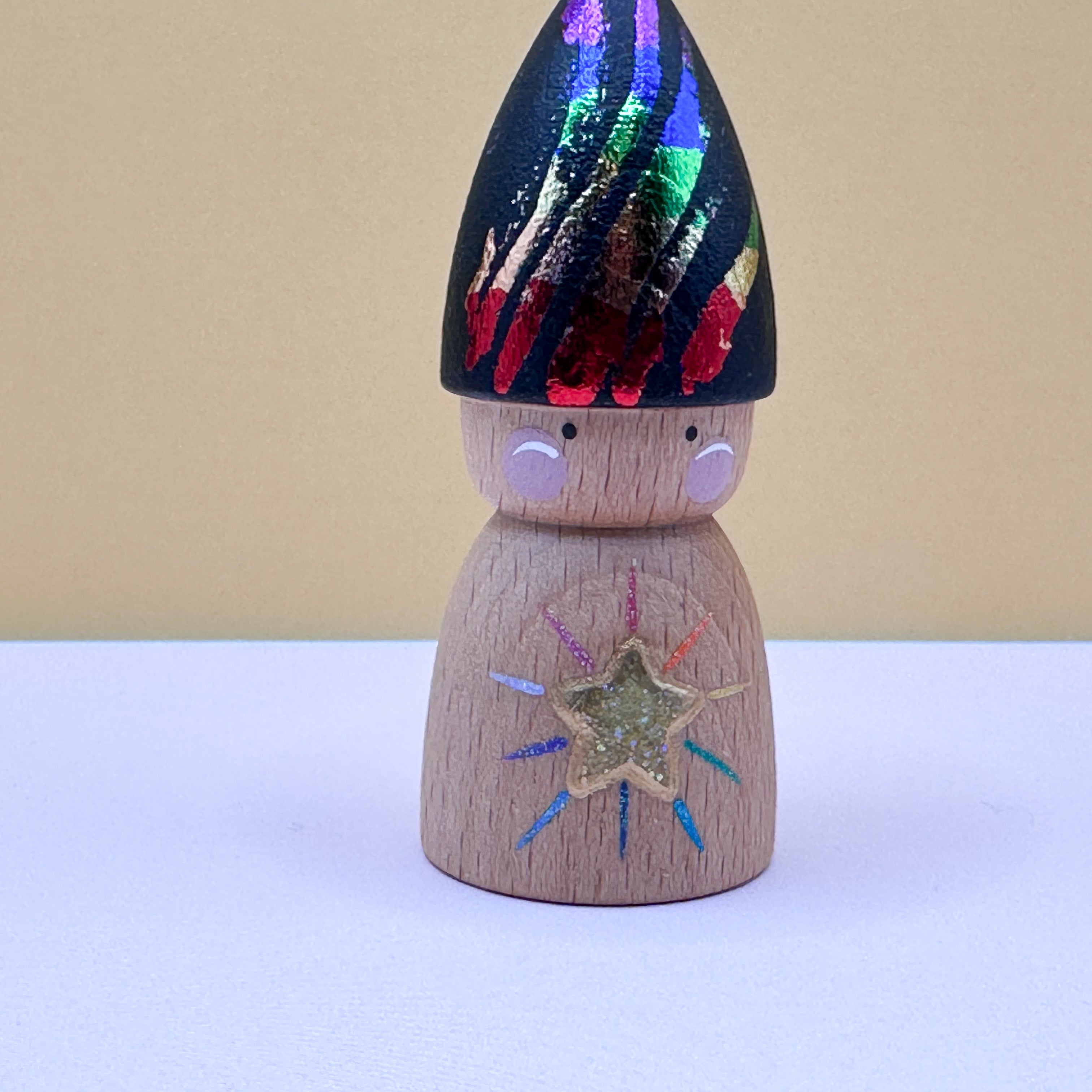 Wooden peg doll with colorful hat and star design on a beige background