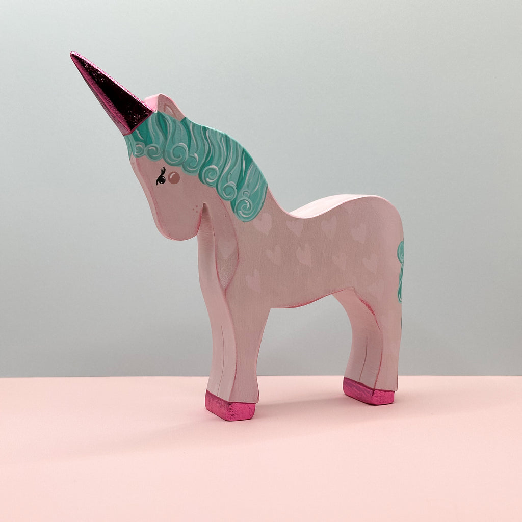 Unicorn figurine with pink body, green mane, and black horn on a light gray background