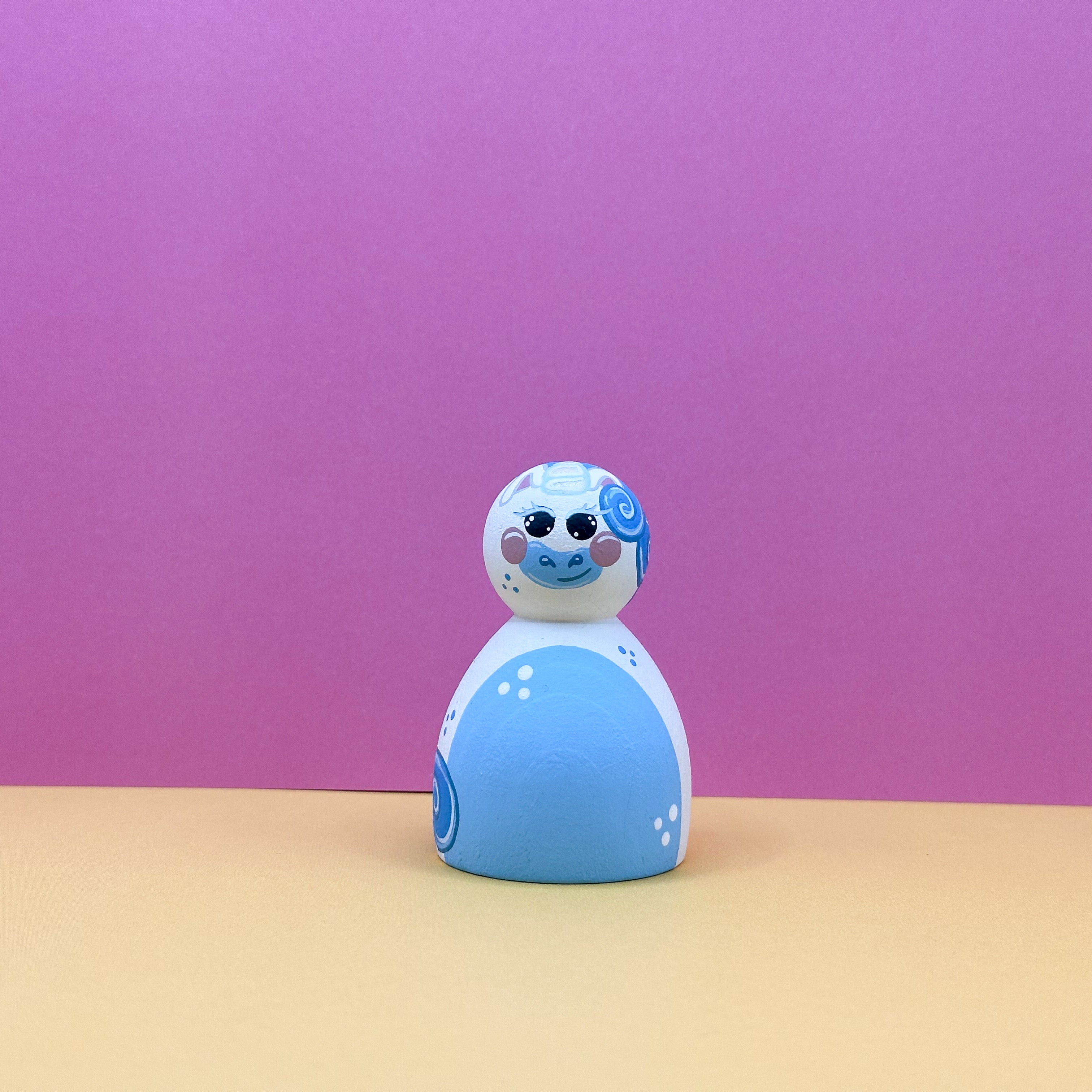 Blue and white figurine with a pink swirl on a pink background