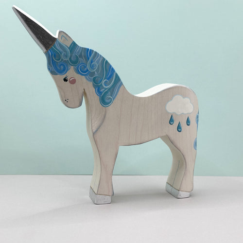Wooden unicorn figurine with blue horn and cloud design on a light green background