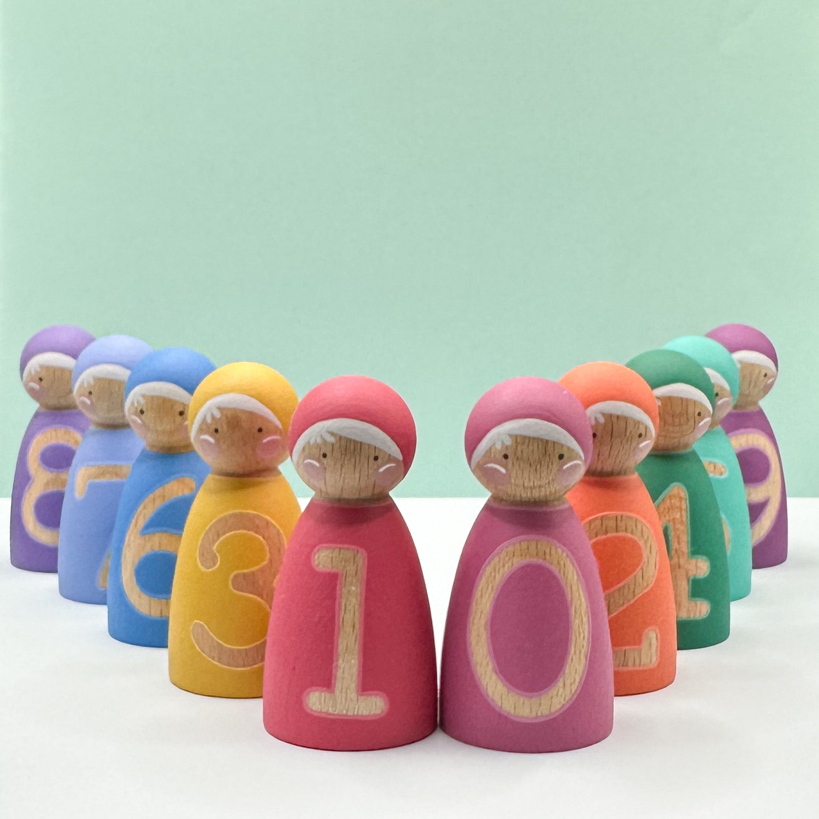 Colorful wooden peg dolls with numbers on a light green background