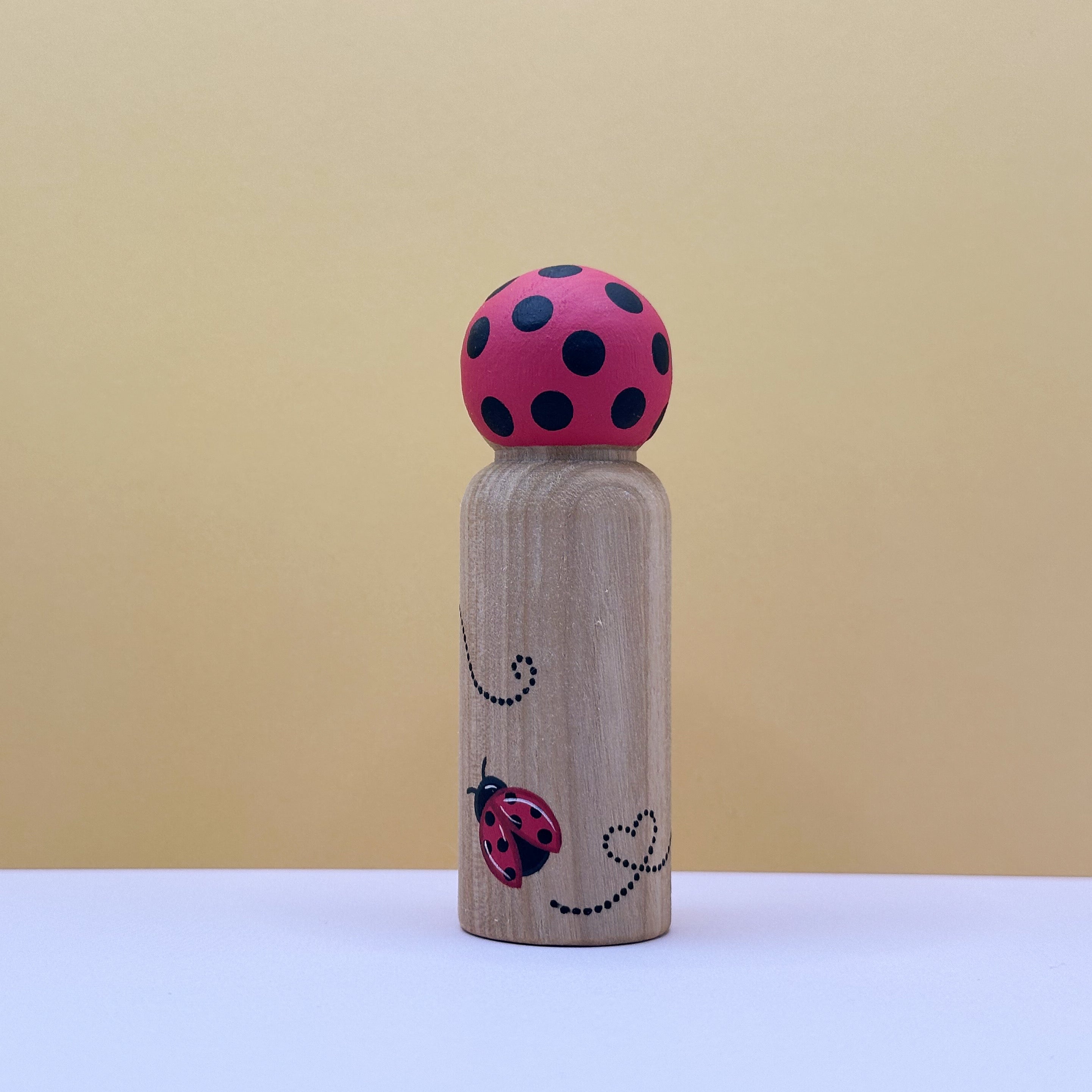 Wooden peg with a red ladybug top on a beige background