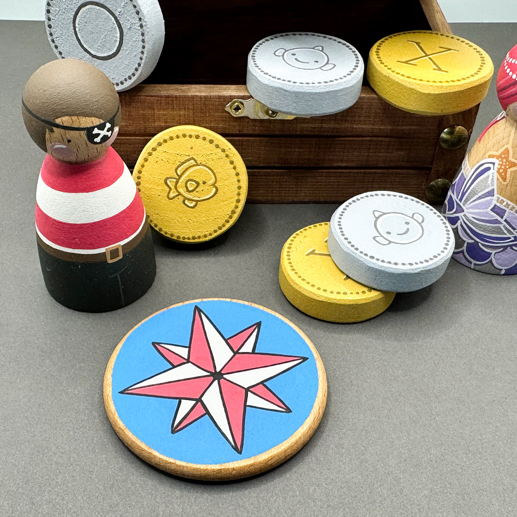 Wooden toy treasure chest with wooden peg dolls, wooden coins and a round disc shaped treasure map