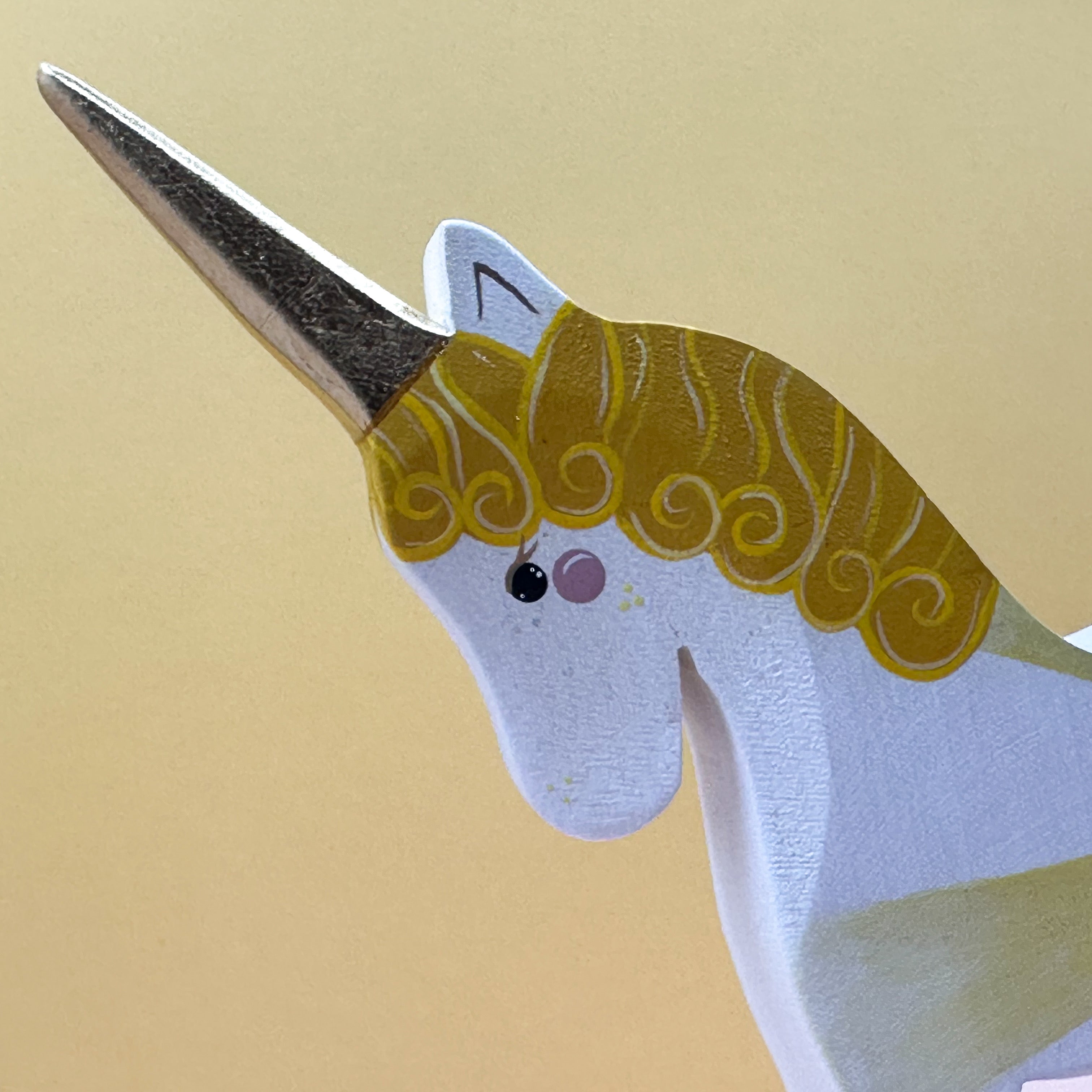 Close-up of a unicorn figurine with a gold horn on a beige background
