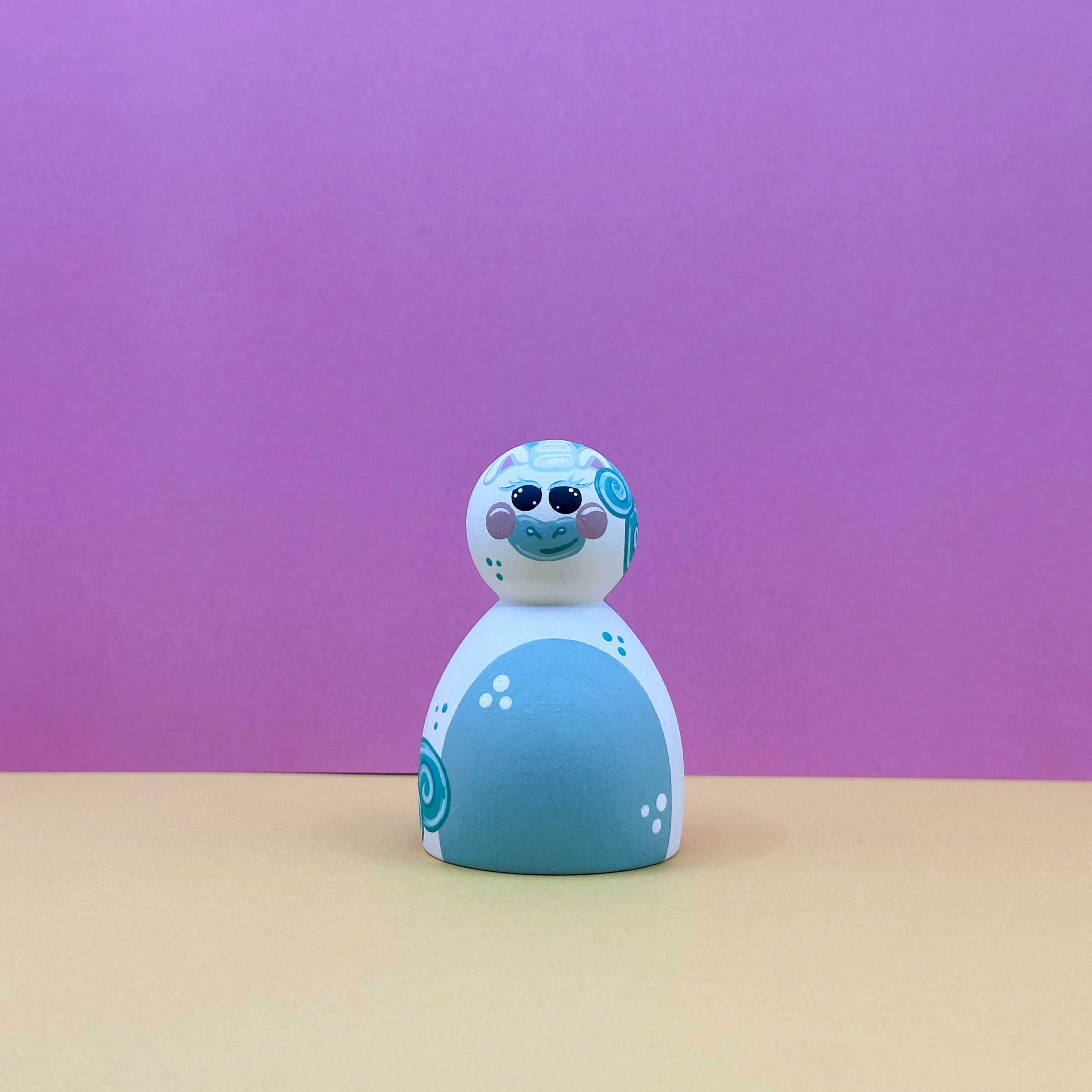 Toy figure with green and white design on a pink background