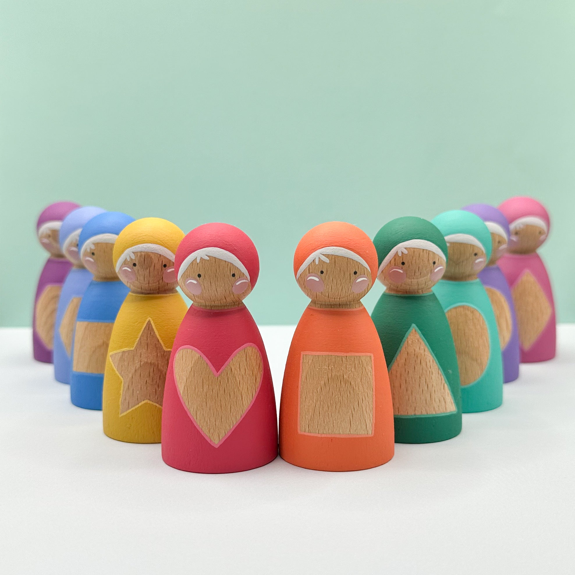 Colorful wooden peg dolls with different shapes on their bodies against a light green background