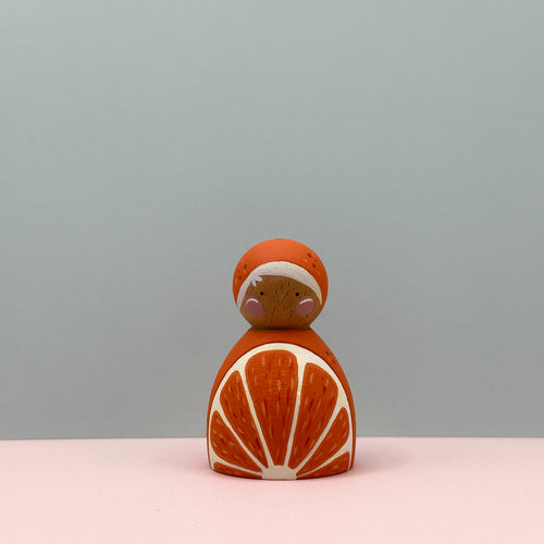 Decorative figurine shaped like an orange with a face on a light gray background
