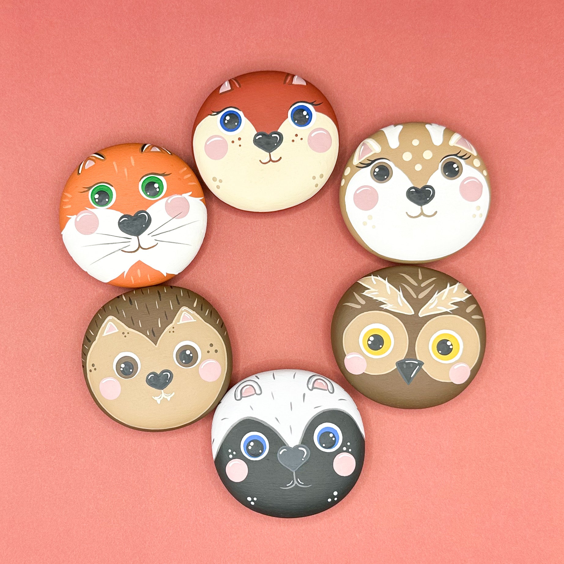 Set of six animal-themed wooden pebbles on a pink background