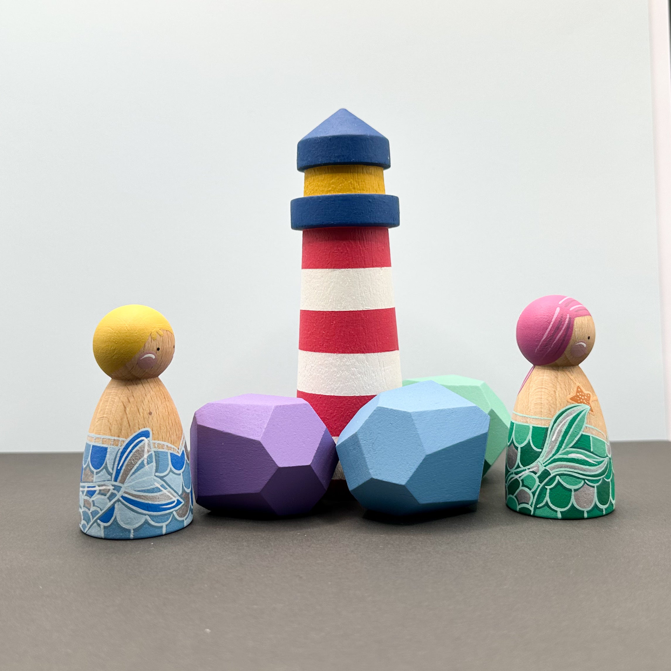 mermaid themed peg doll toys with wooden rocks and a lighthouse. 