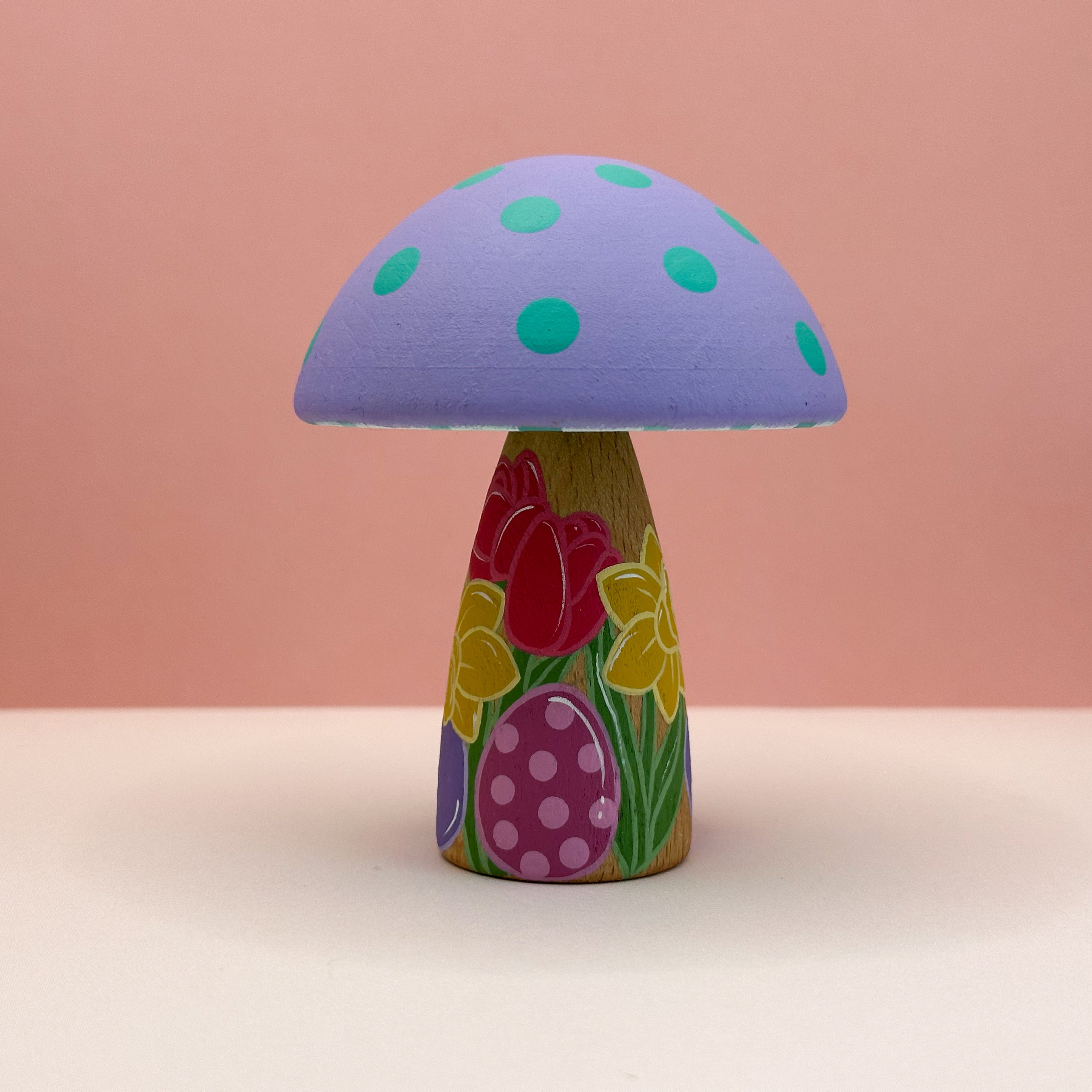 Colorful mushroom-shaped object with a purple cap and floral design on a pink background