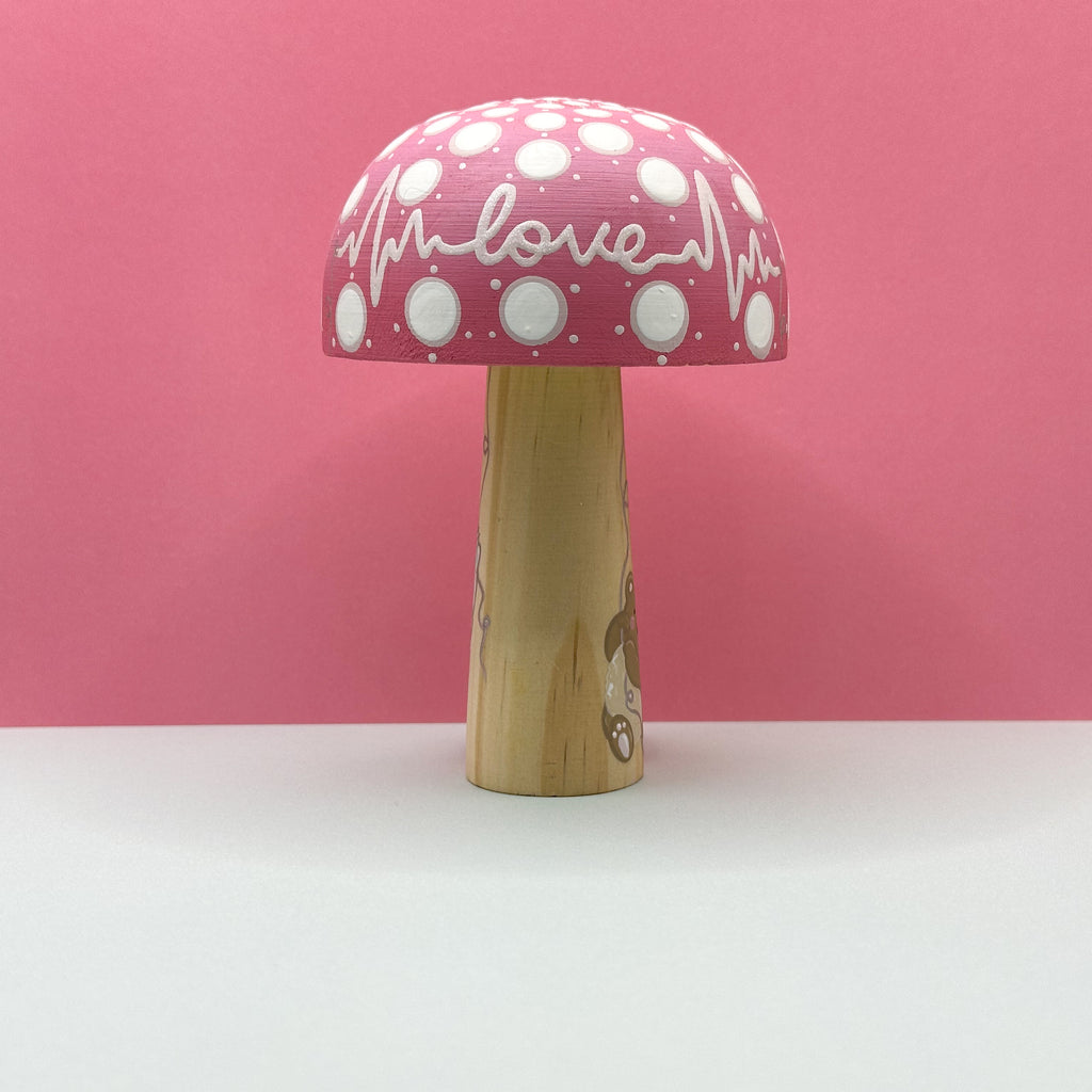 Mushroom-shaped toy with pink polka dot shade and wooden base on a pink background