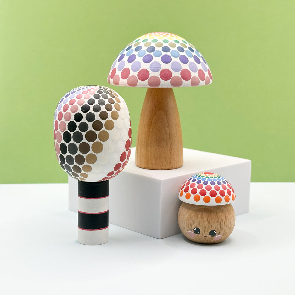 Three colorful mushroom-shaped objects on a white surface with a green background