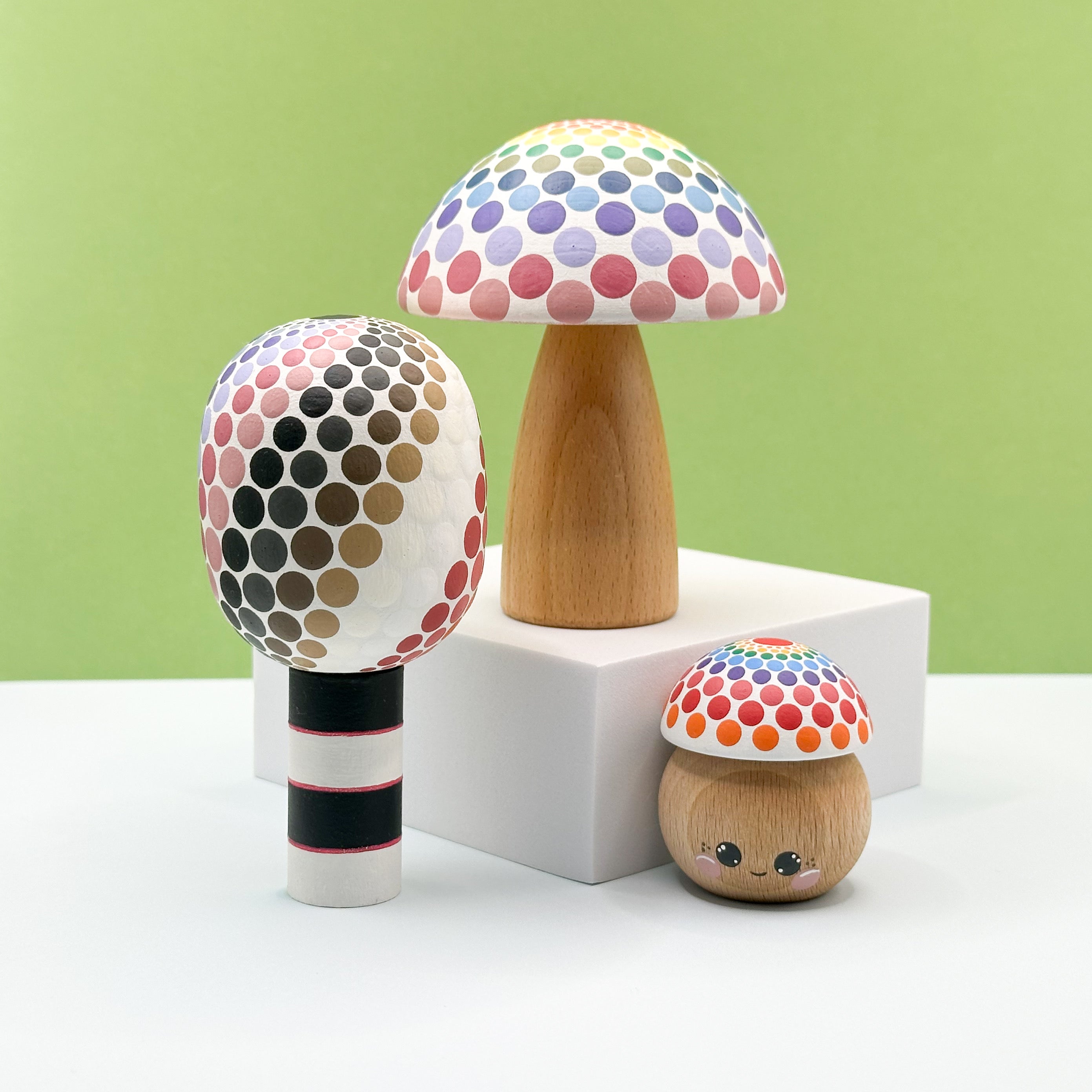 Three colorful mushroom-shaped objects on a white surface with a green background