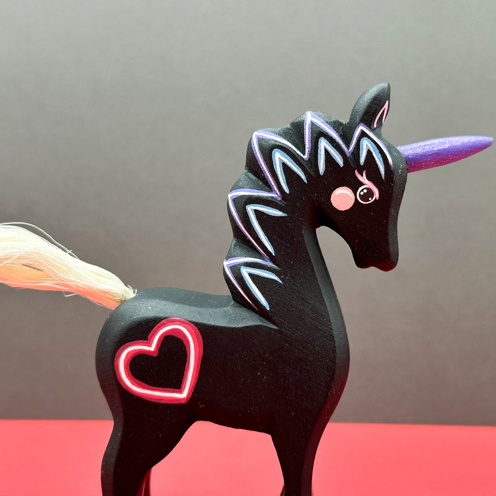 Black unicorn figurine with neon accents on a red surface