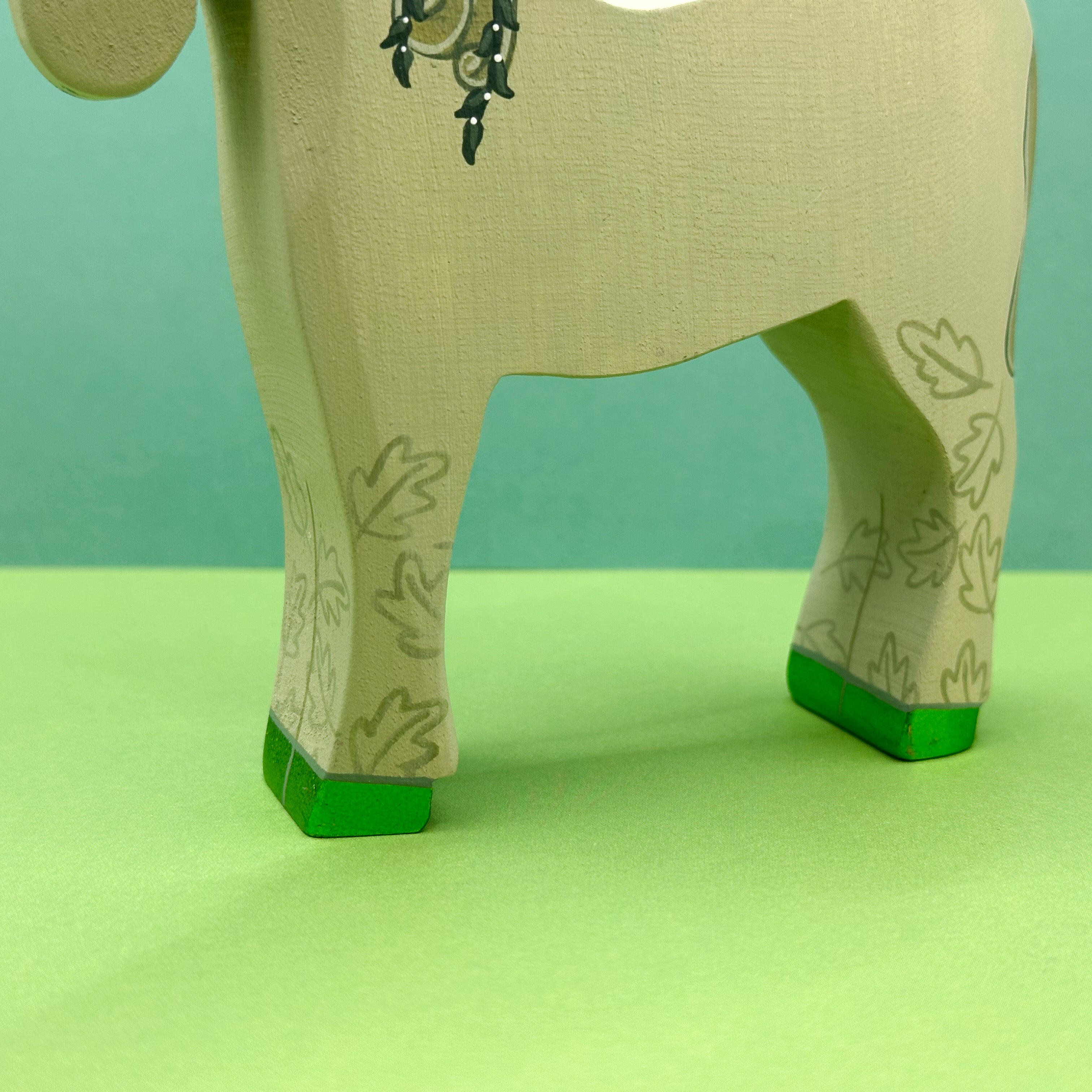 Close-up of a green unicorn figurine with green feet on a green background