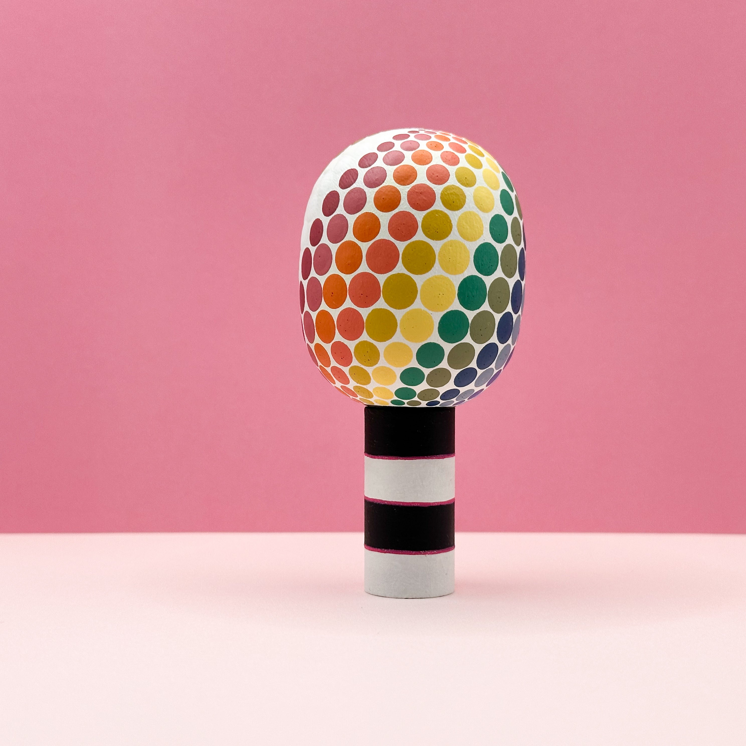 Colorful polka dot object on a pink background