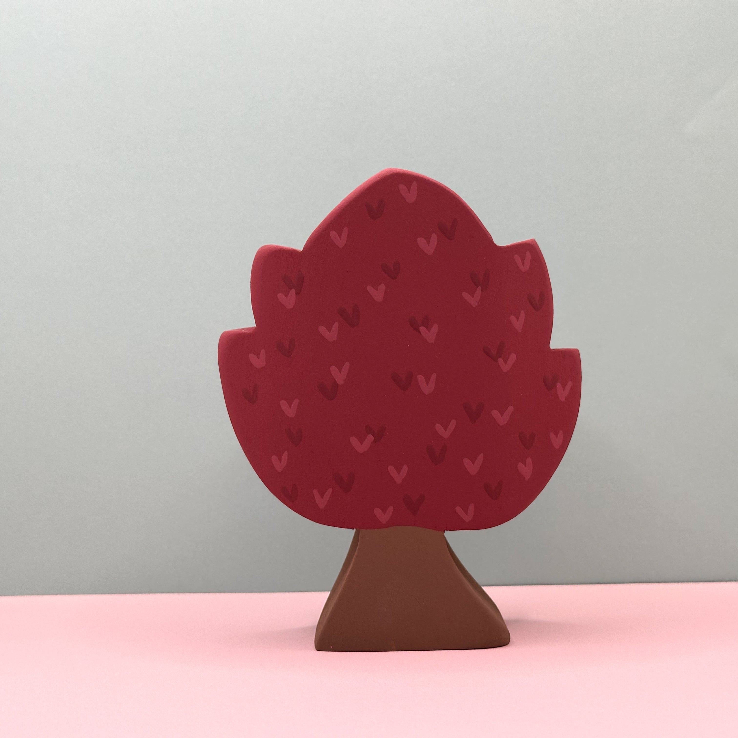 Red tree-shaped object on a pink surface with a gray background