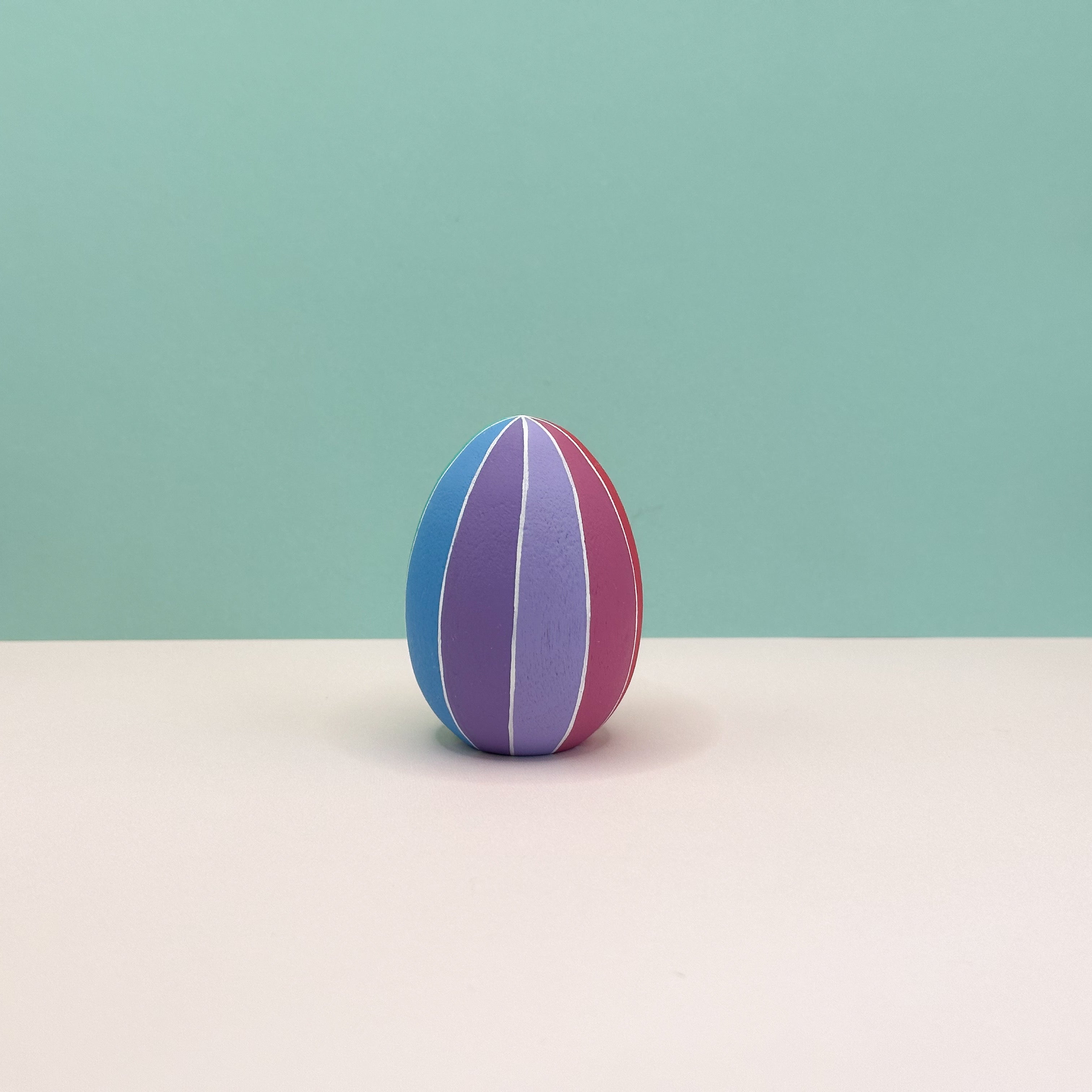 Colorful striped egg on a light surface with a light green background