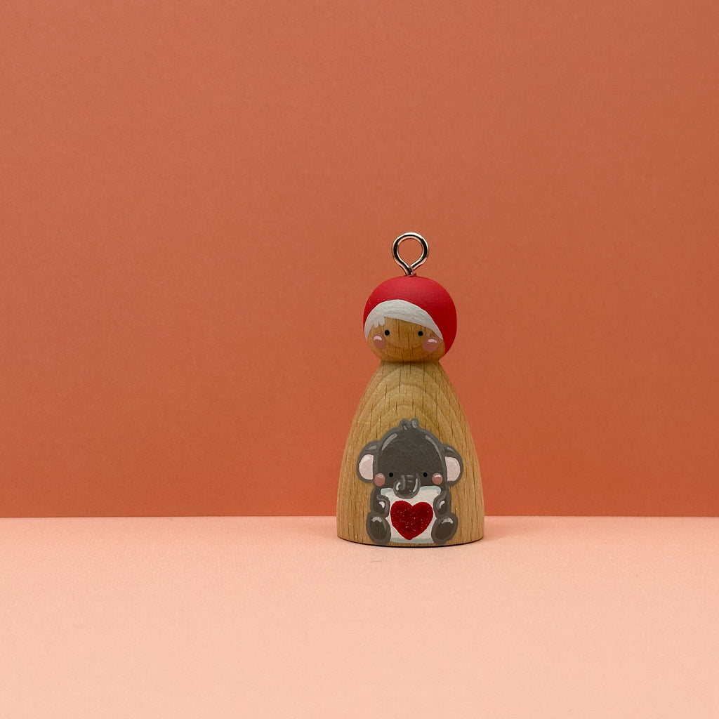 Small peg doll keyring with an elephant holding a heart sign painted on its body with a peach background