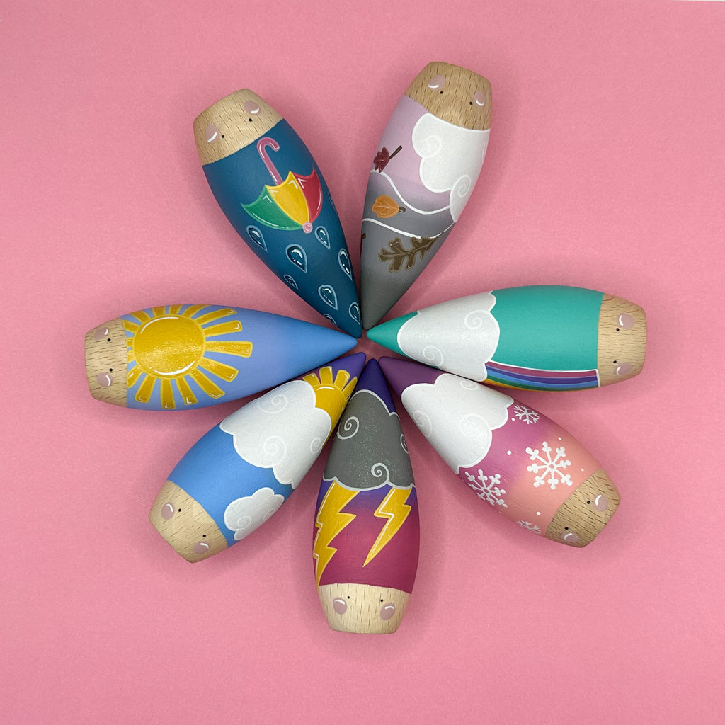 Colorful wooden toys shaped like weather icons on a pink background