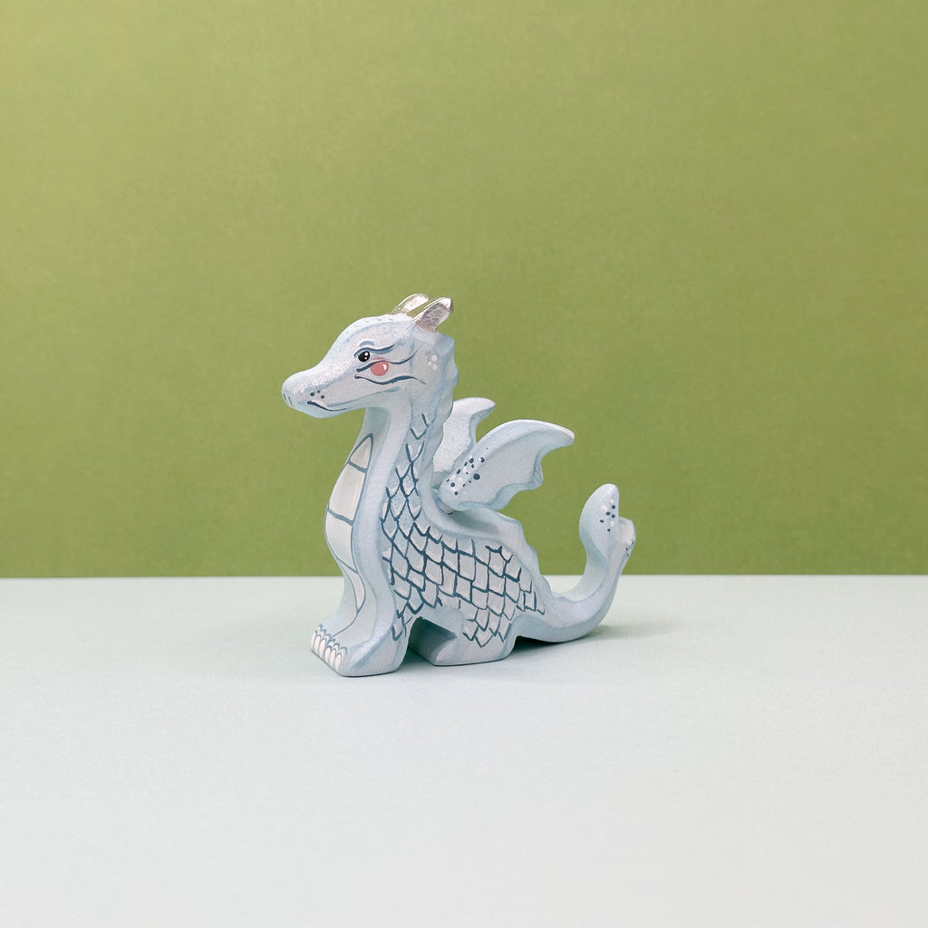 A small wooden light blue dragon on a green background