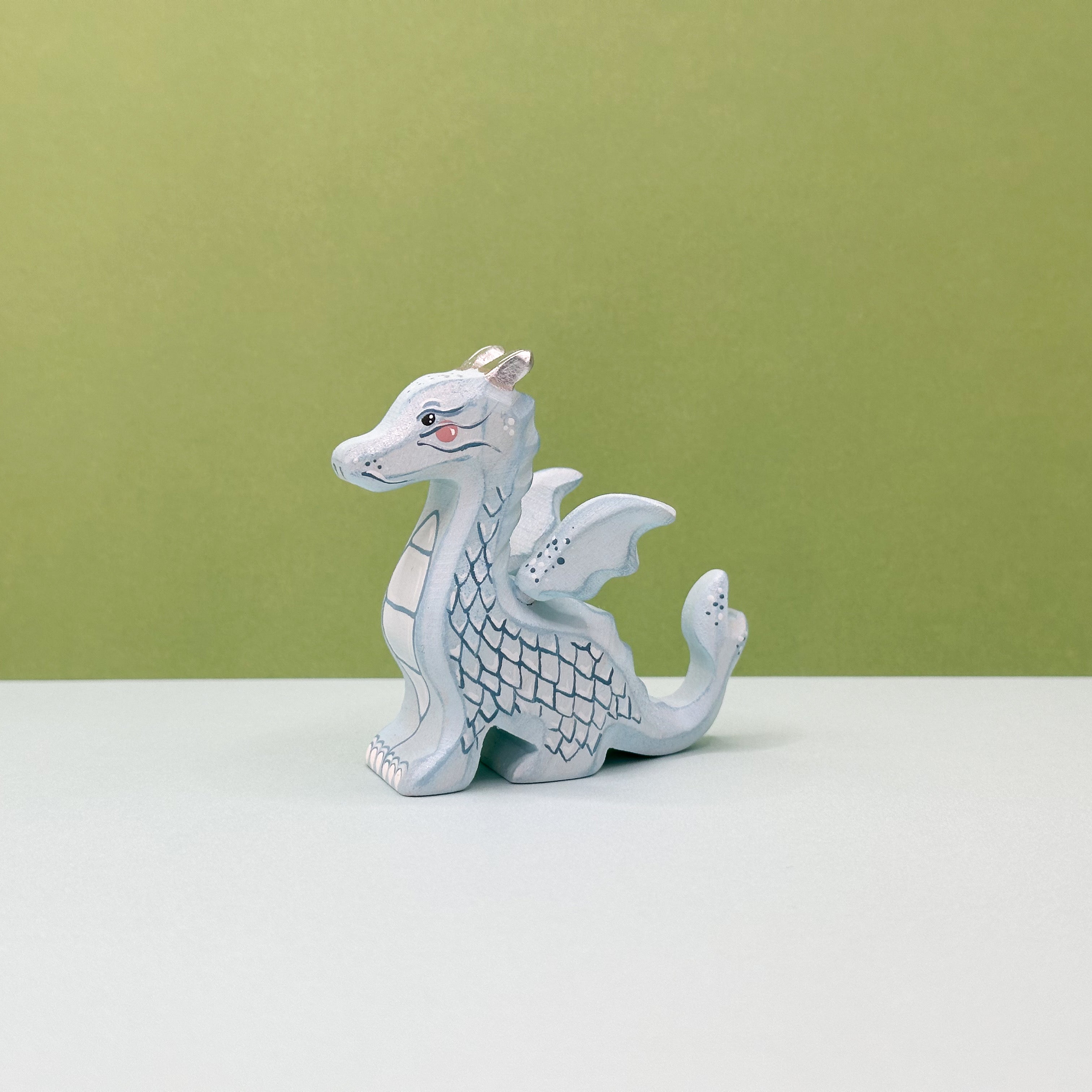A small wooden light blue dragon on a green background