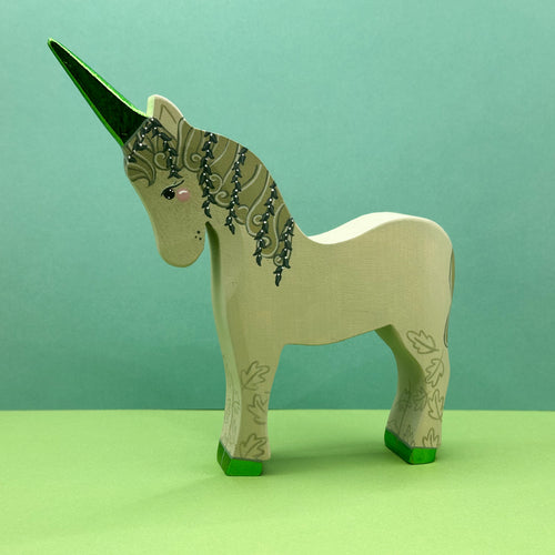 Wooden unicorn figurine with green base and decorative elements on a green background