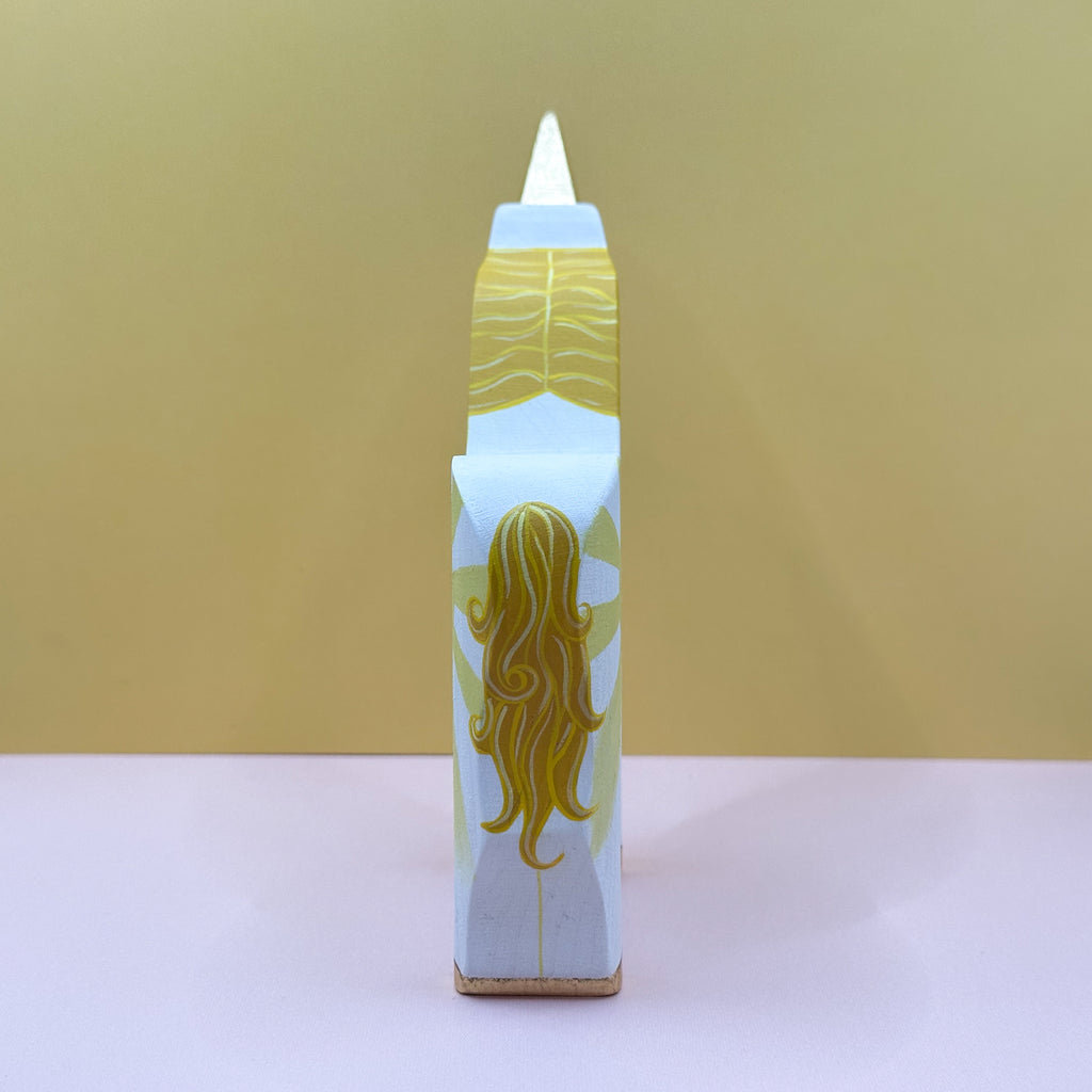 Wooden unicorn with a yellow tail on a beige background