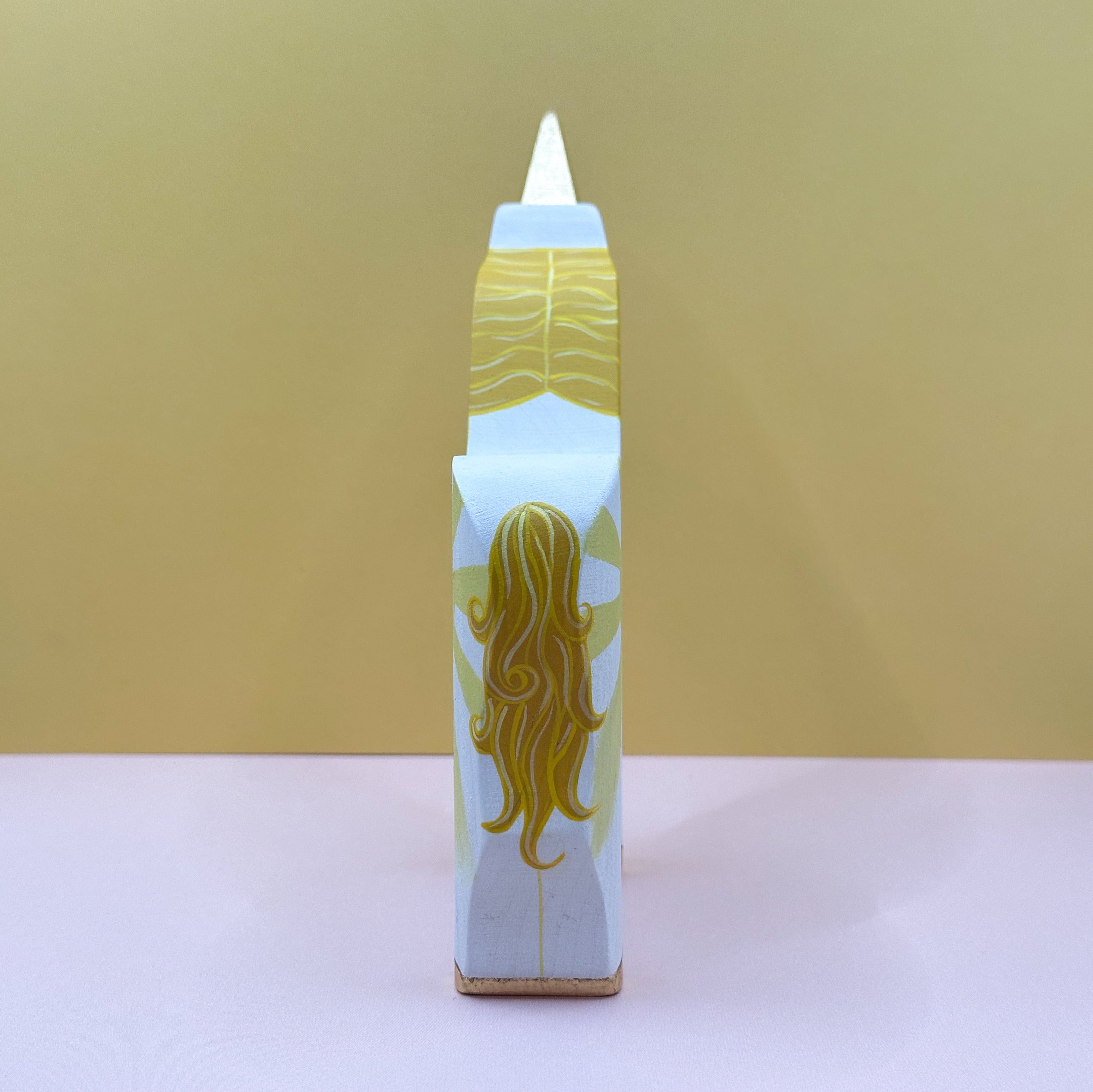 Wooden unicorn with a yellow tail on a beige background