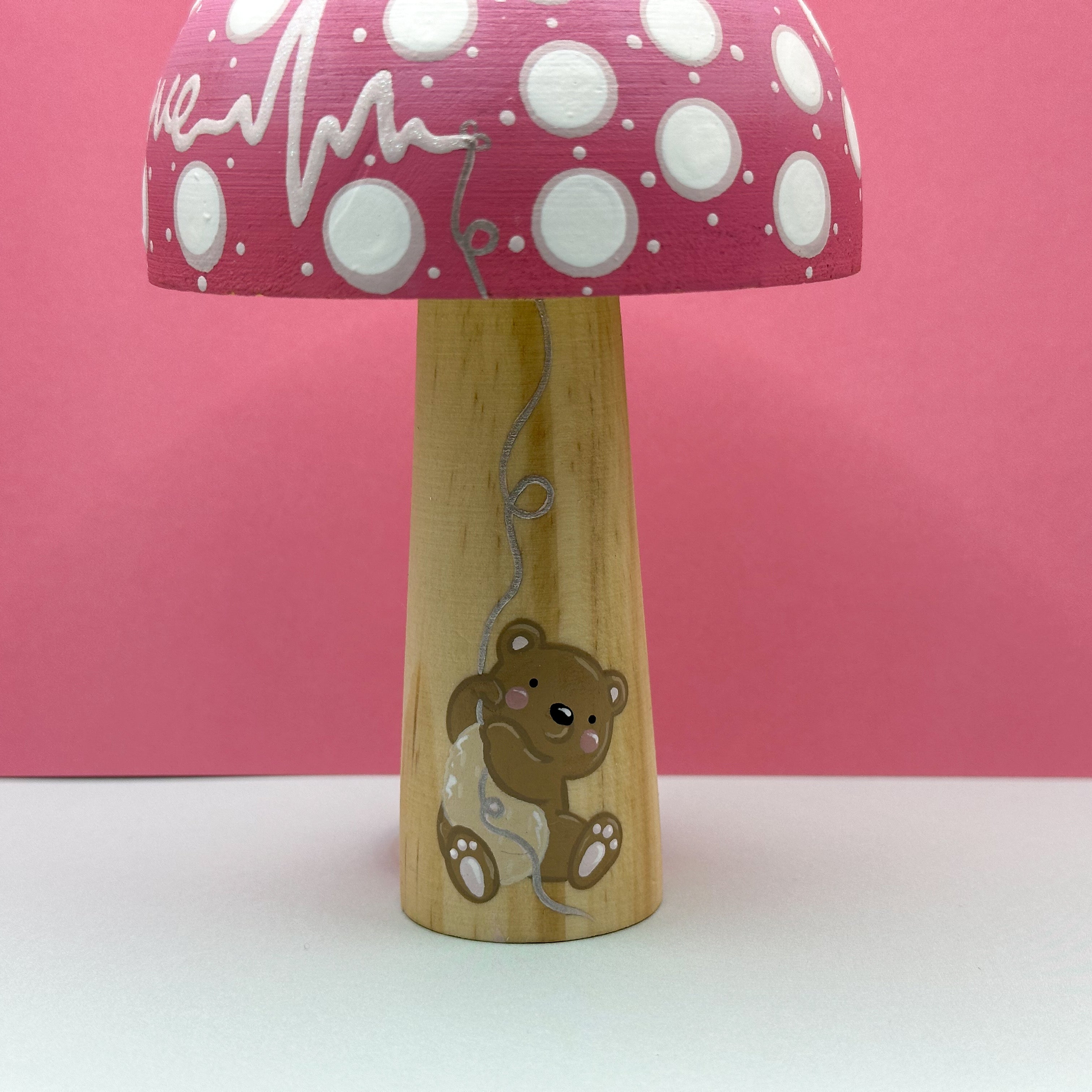 Wooden toy with pink polka dot pattern and bear design on a pink background