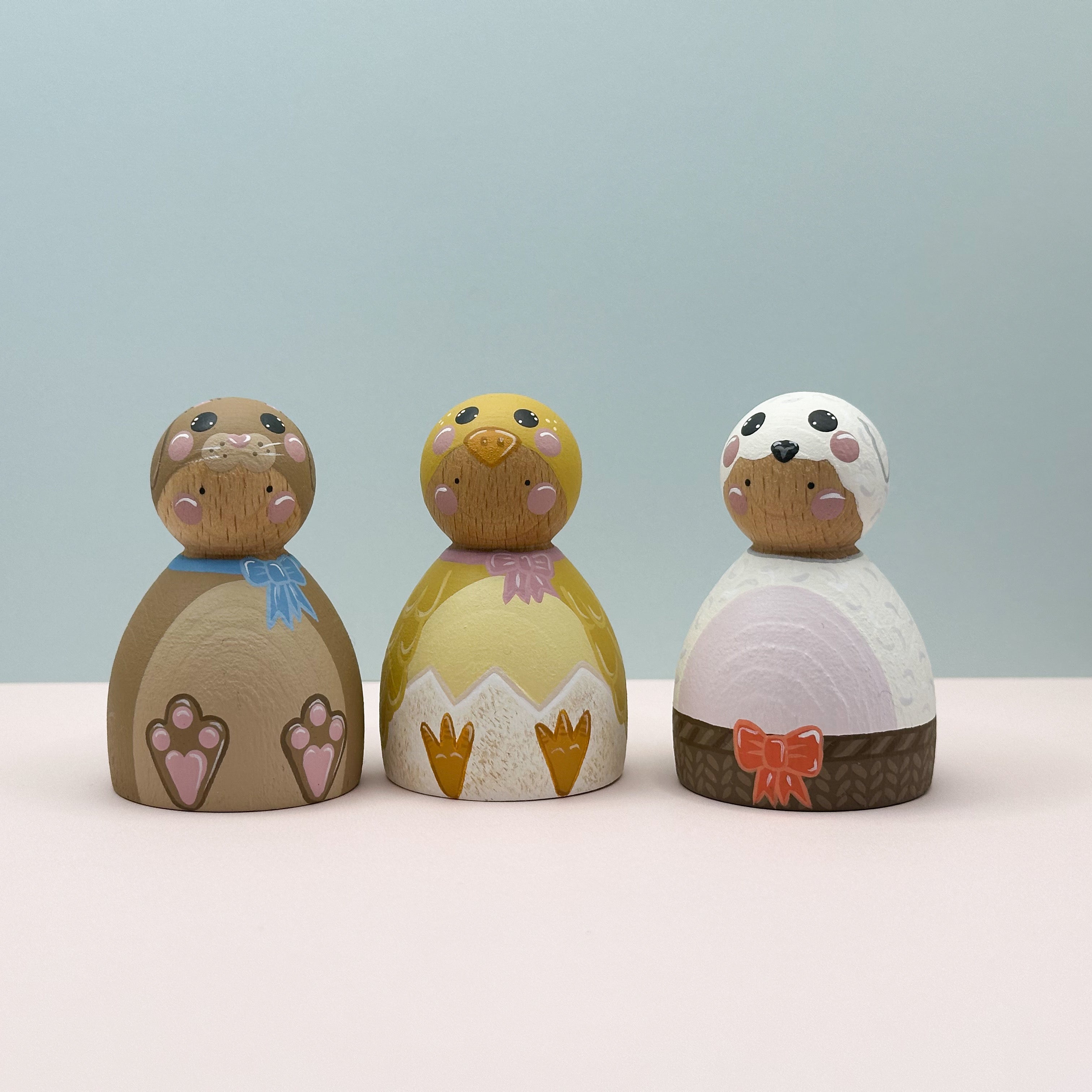Three wooden figurines with colorful designs on a light blue background