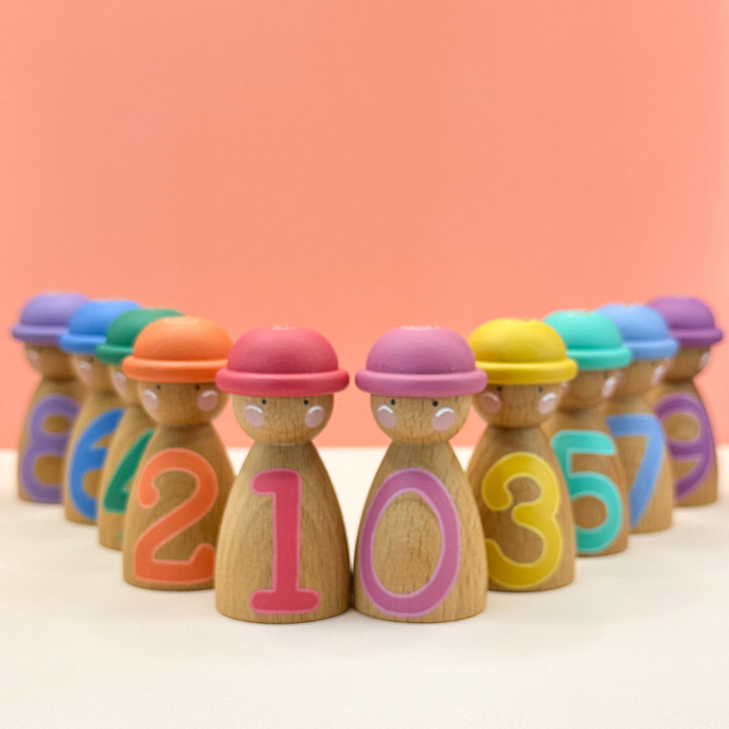 Set of wooden peg dolls with colorful numbers on a pink background