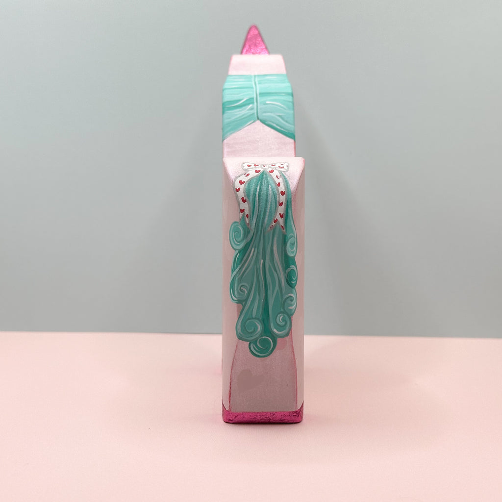Tail view of a pink unicorn with a teal tail on a light gray background