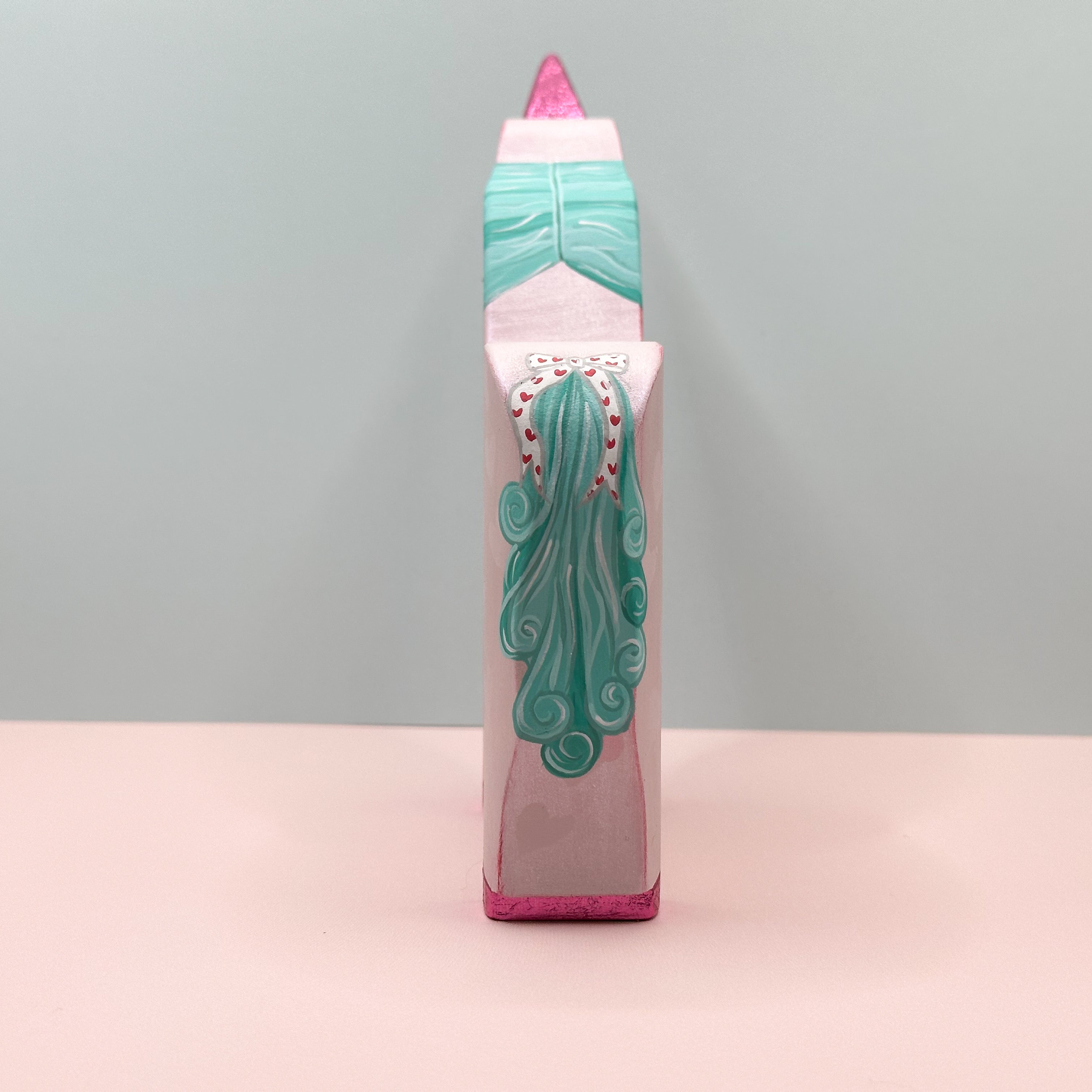 Tail view of a pink unicorn with a teal tail on a light gray background